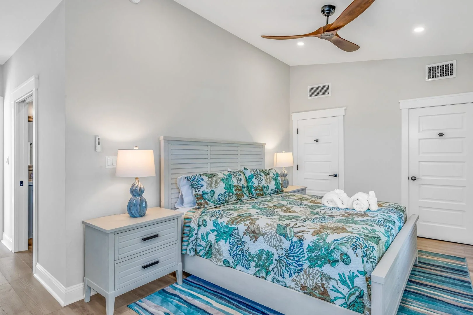 Elegant bedroom with wooden bed, ocean view, and sunset in window.