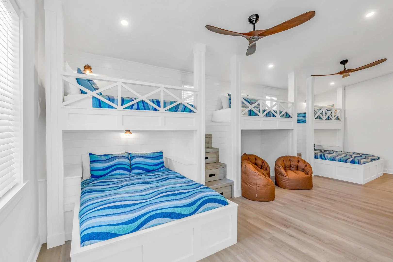Modern bedroom with a bed, nightstands, dresser, TV, and bathroom entrance. Features hardwood flooring, a rug, potted plant, and ceiling fan.