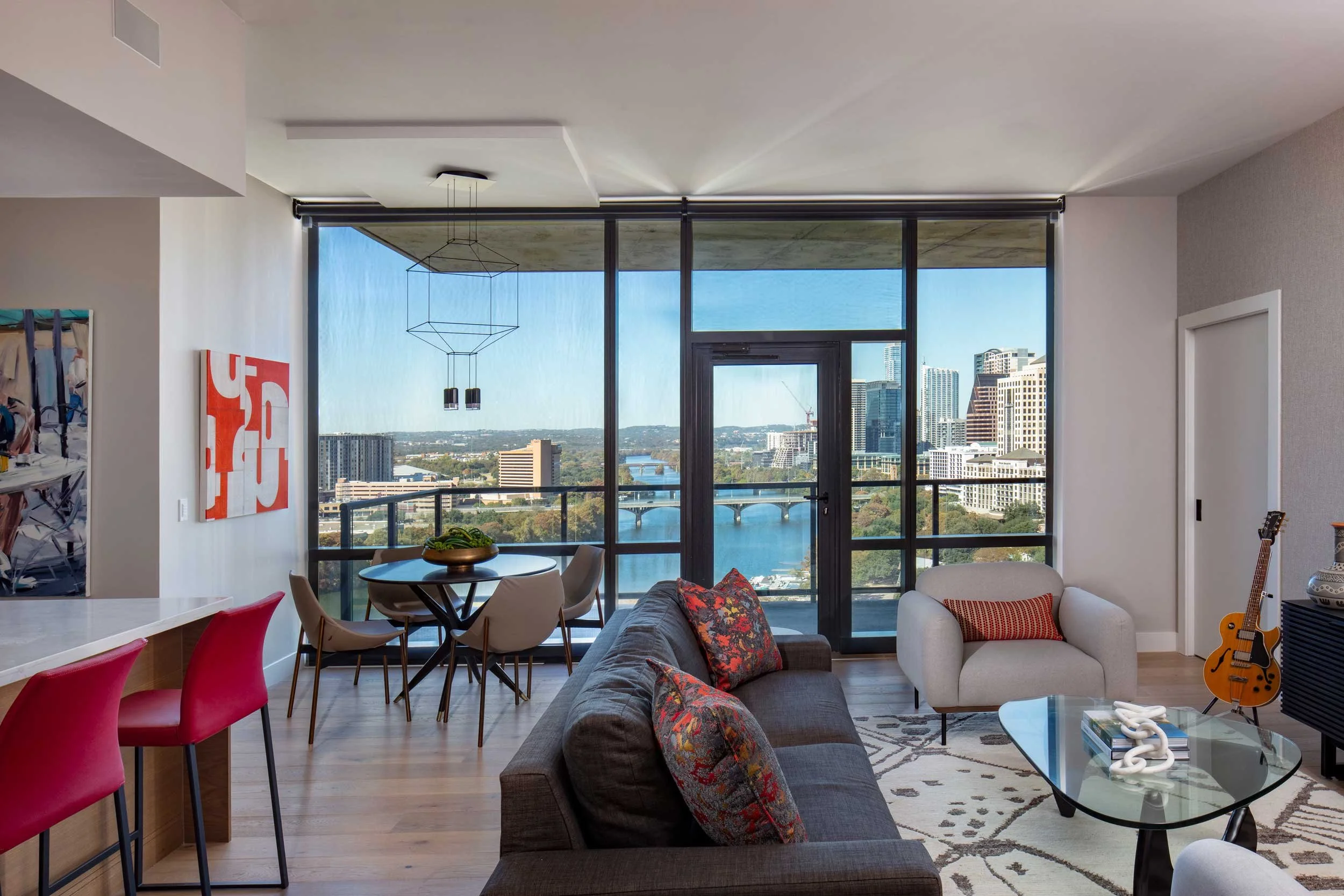 Modern condo living space by Dawn Hearn Interior Design in Austin, Texas, featuring bold contemporary furnishings, vibrant accents, and stunning city and river views.