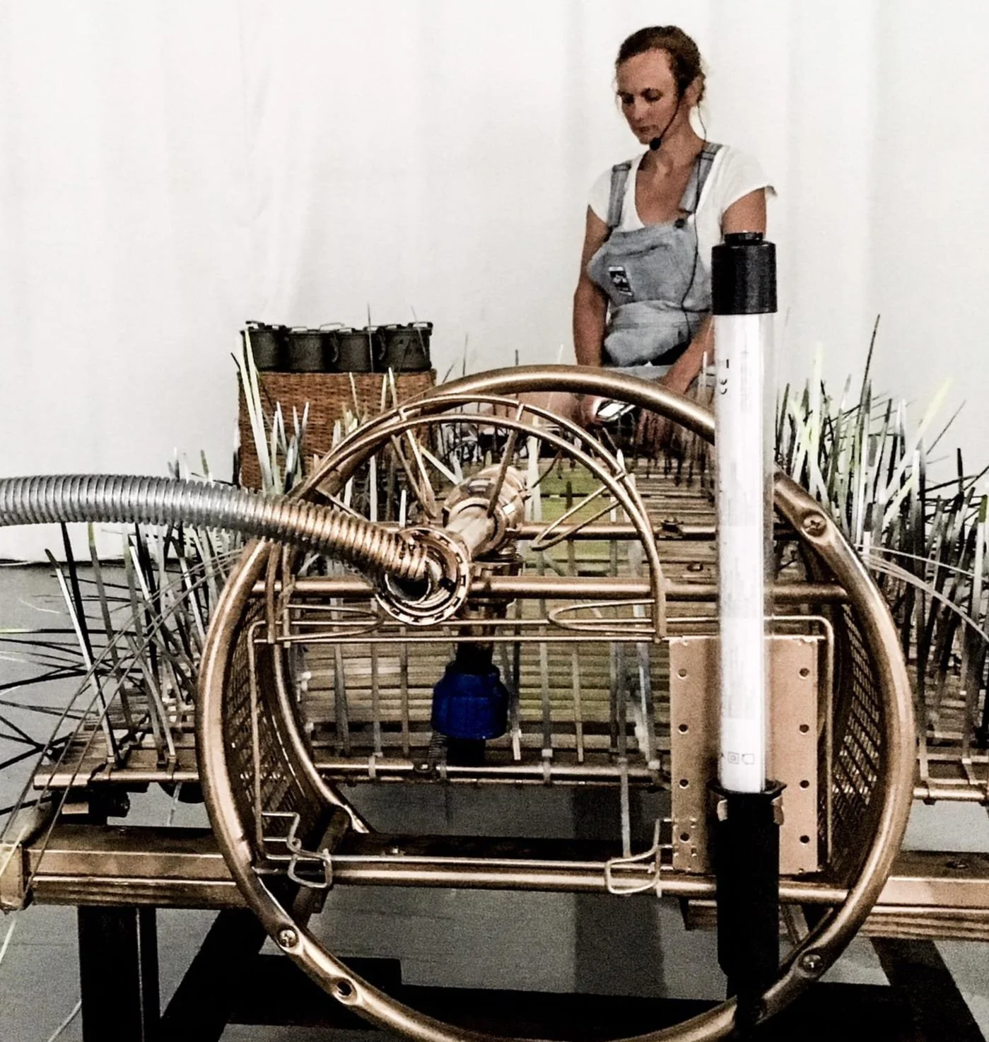 Eine Frau prüft ein komplexes mechanisches Gerät, vermutlich eine Maschine, in einem Museum oder Ausstellungsraum.