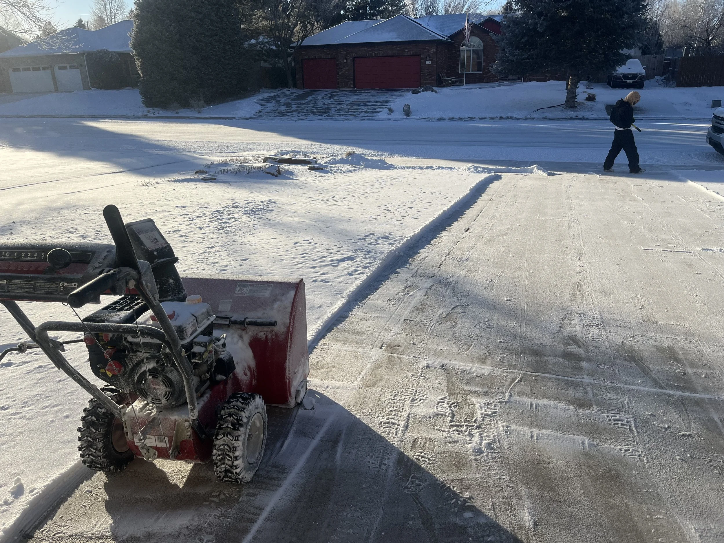 Whipper Snapper Lawn Care providing residential snow removal with a snow blower to clear a driveway and sidewalk