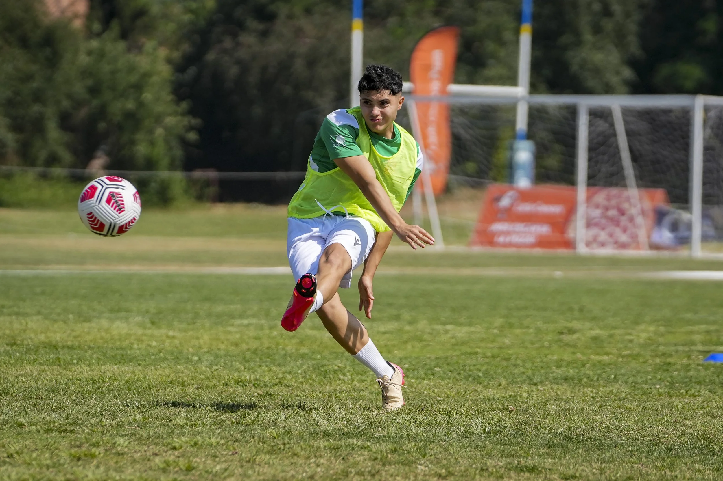 Joven futbolista en acción pateando un balón en el campo de entrenamiento