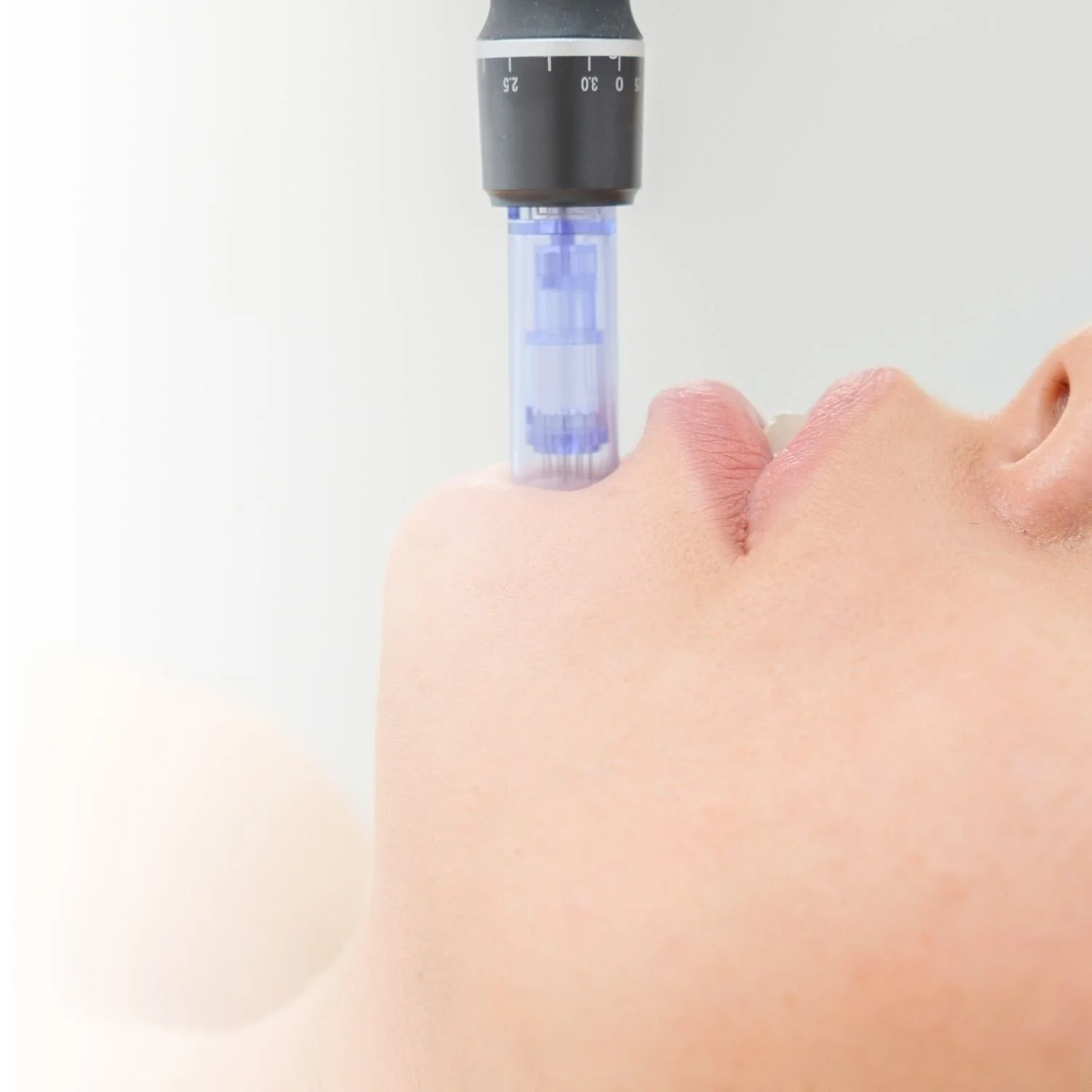 Dermapen microneedling device on a woman's chin during a facial treatment.