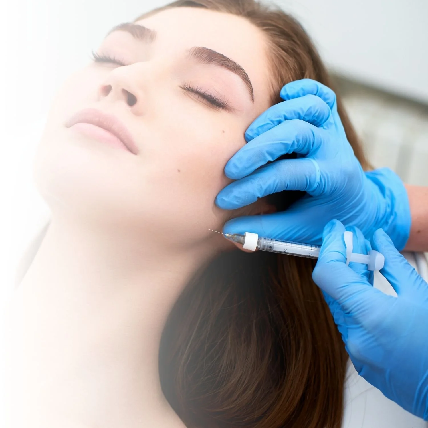 Woman receiving a facial injection by a person wearing blue gloves.