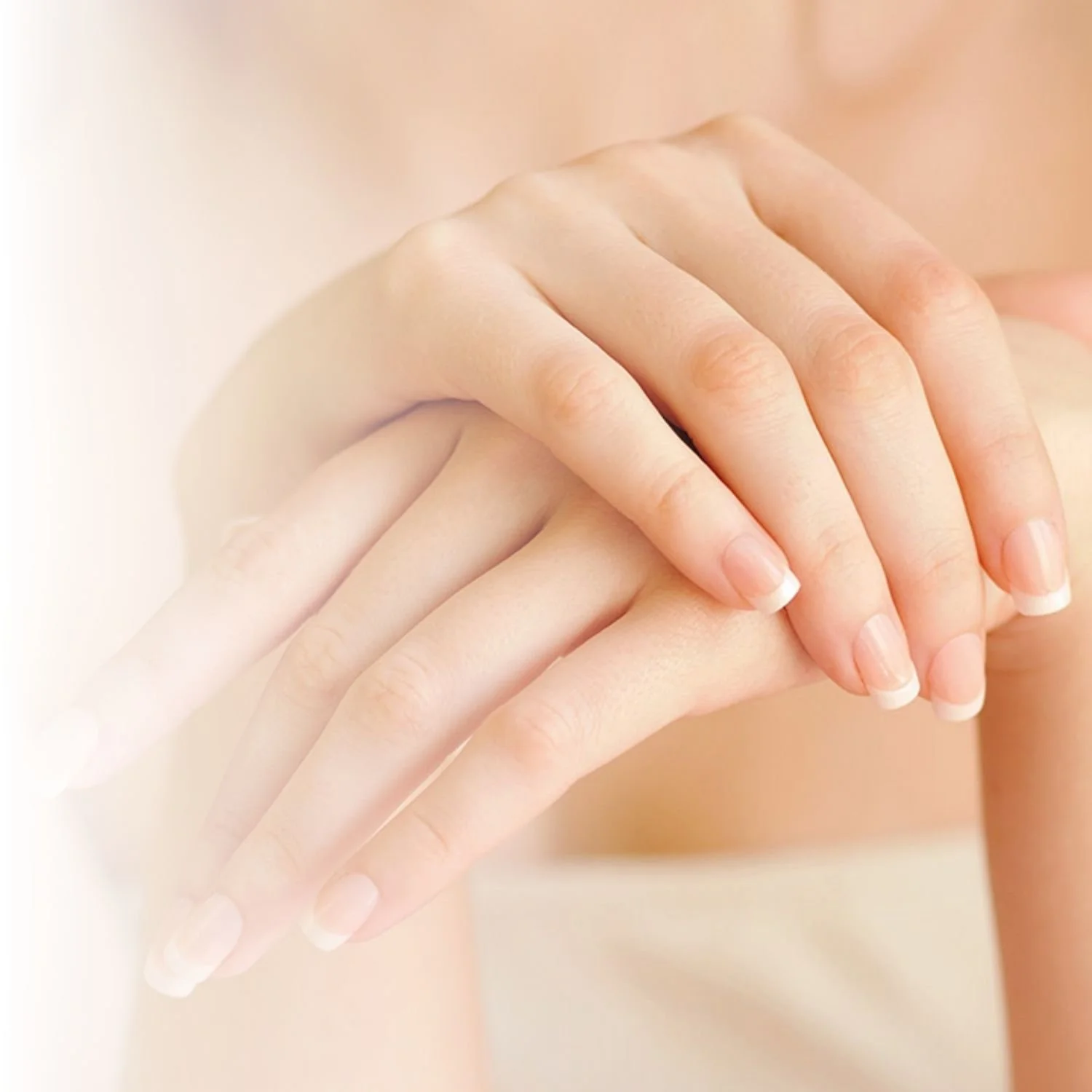 Close-up of hands with manicured nails, gently resting on each other against a soft background.