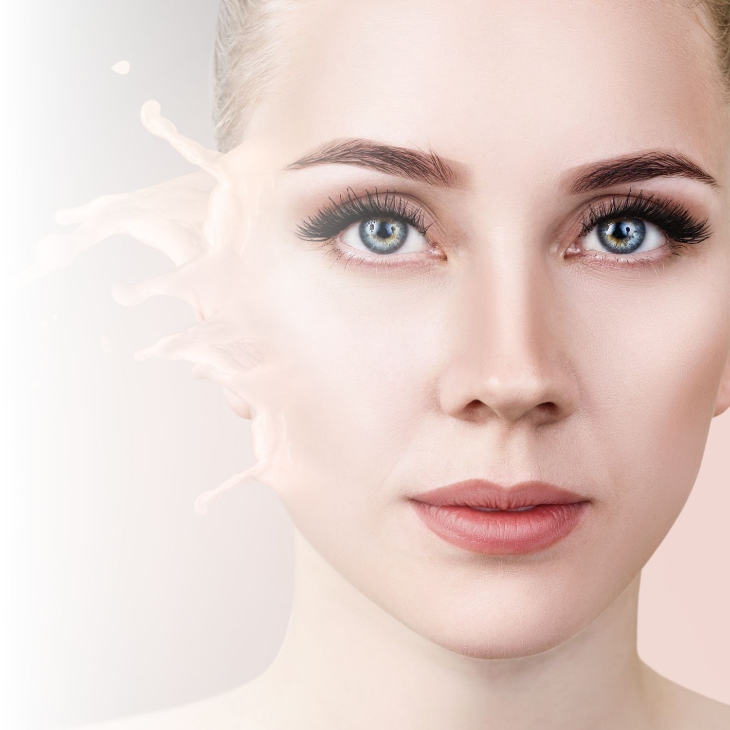 Close-up of a woman's face with smooth skin and a splash of cream or liquid on the side.