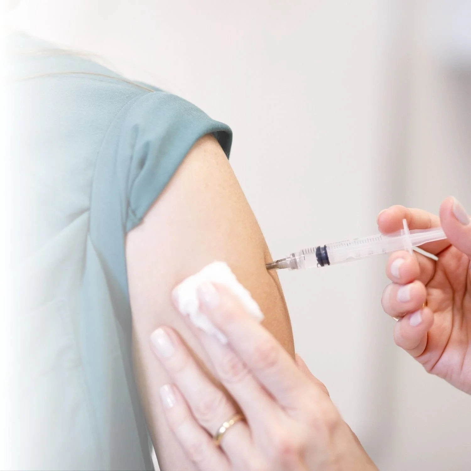 A person receiving a vitamin injection of B12 with a syringe in their upper arm.