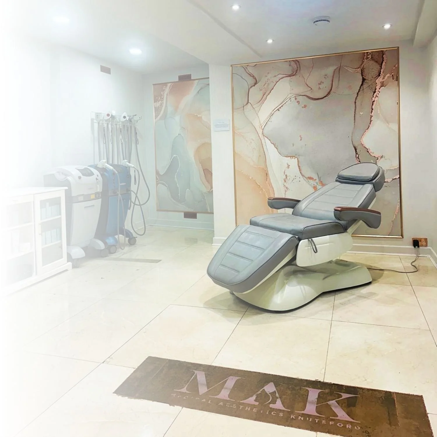 Medical treatment room with adjustable recliner chair, colorful abstract wall art, and medical equipment