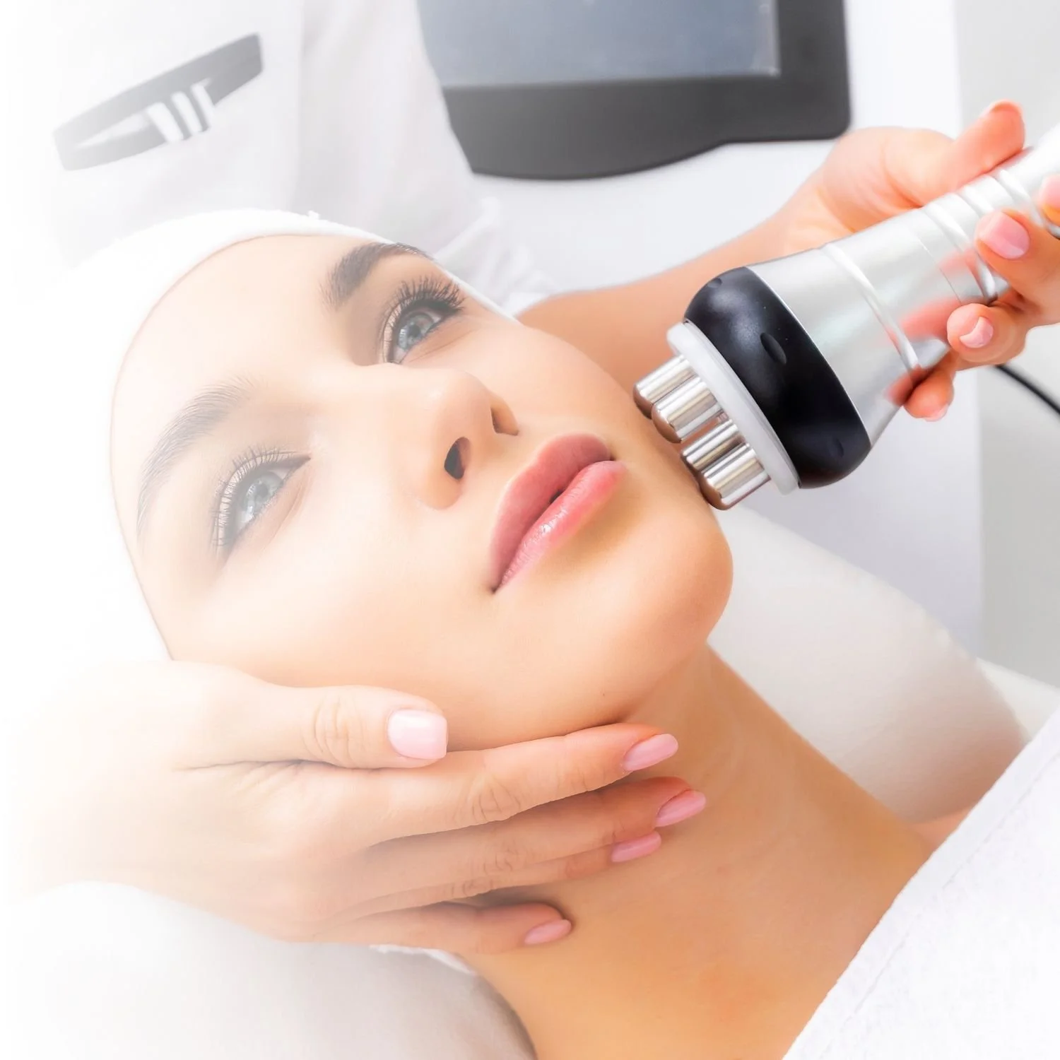 A woman receiving a facial treatment with a handheld device in a spa setting.