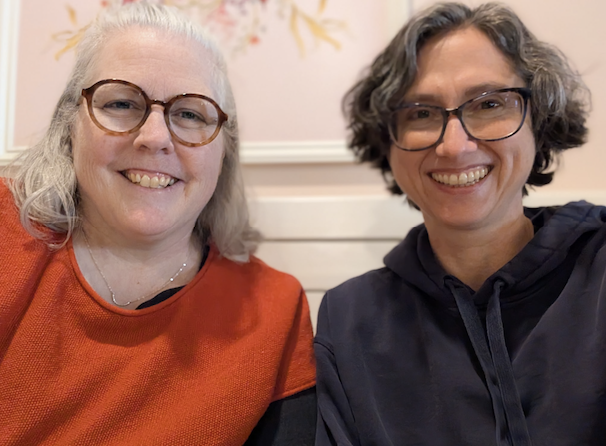 Amy Noyes and Miranda Jane, two ADHD/AUDHD/Autistic support coaches. Amy wears an orange sweater. Miranda wears a blue hoodie.