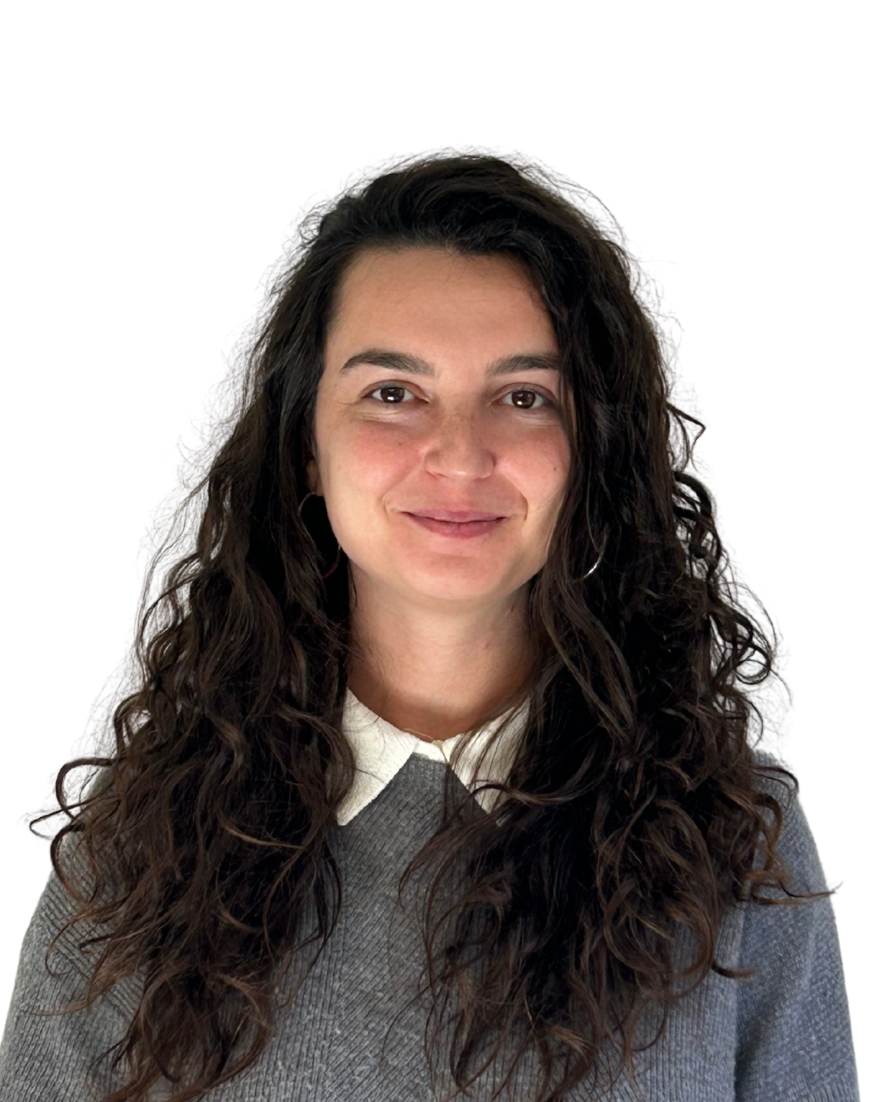 A woman with long, curly dark hair smiling at the camera against a white background.