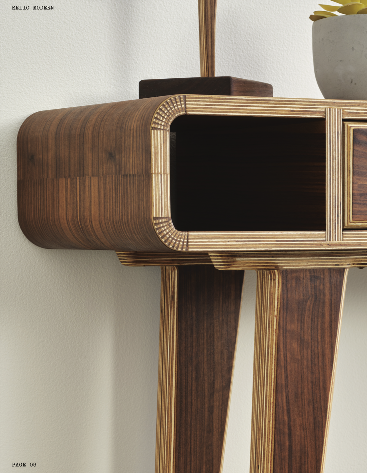 Close-up of a modern wooden side table with rounded edges and a rectangular open compartment, placed against a light-colored wall, with a ceramic pot containing a yellow succulent plant on top.