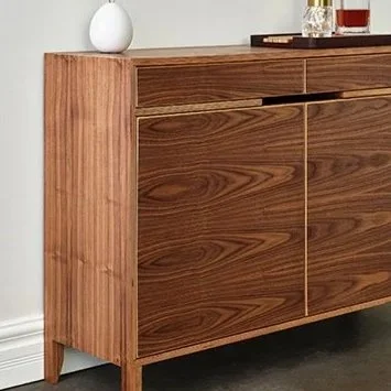 Wooden sideboard with a white vase and glass bottles on top