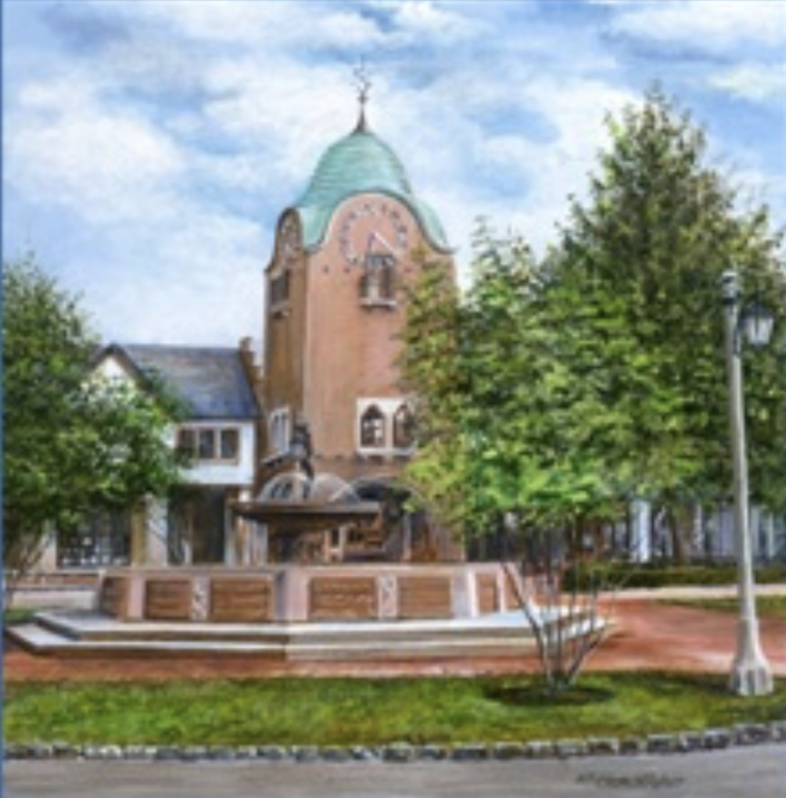 A historic building with a clock tower, surrounded by green trees, a fountain, and a vintage lamp post in a small town square under a partly cloudy sky.