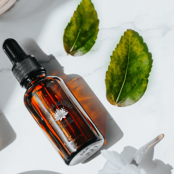 Amber dropper bottle with herbs on white surface