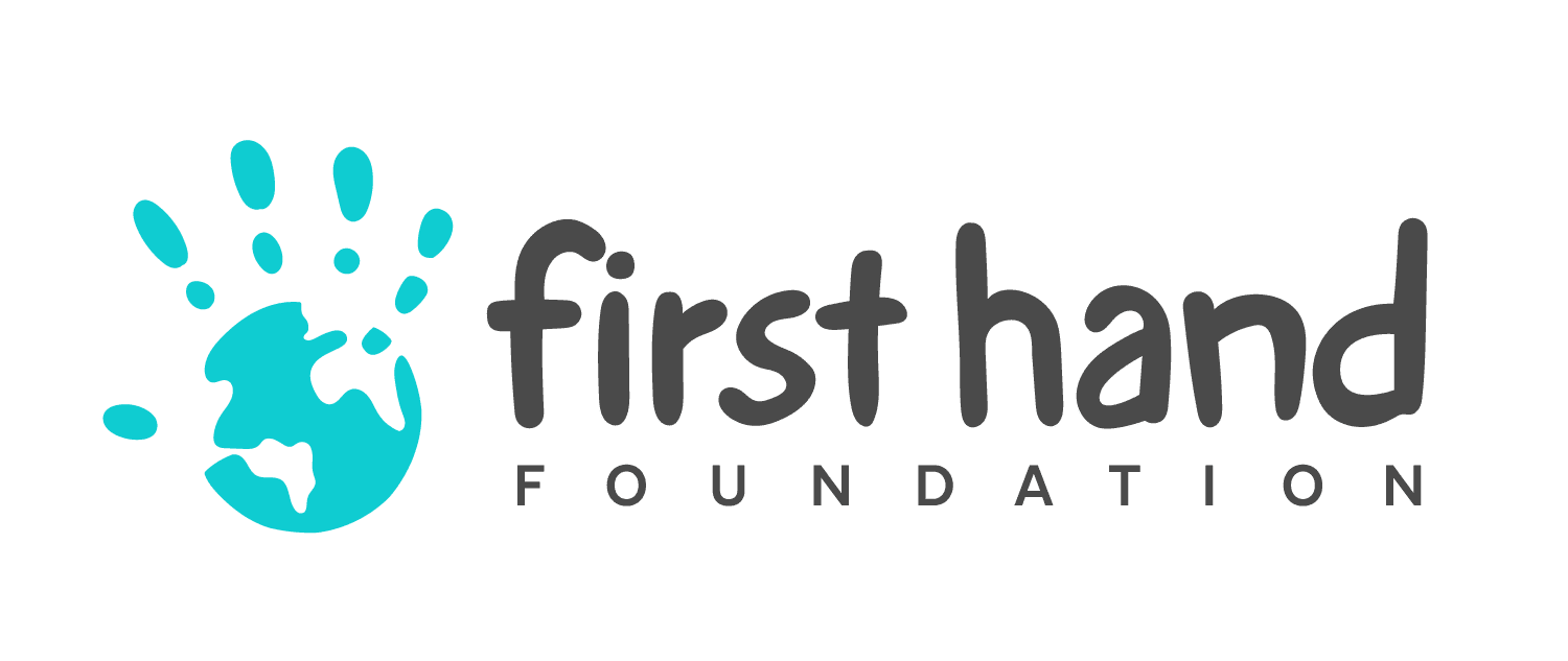 Logo of the First Hand Foundation featuring a blue globe with handprints and the foundation name in black text.