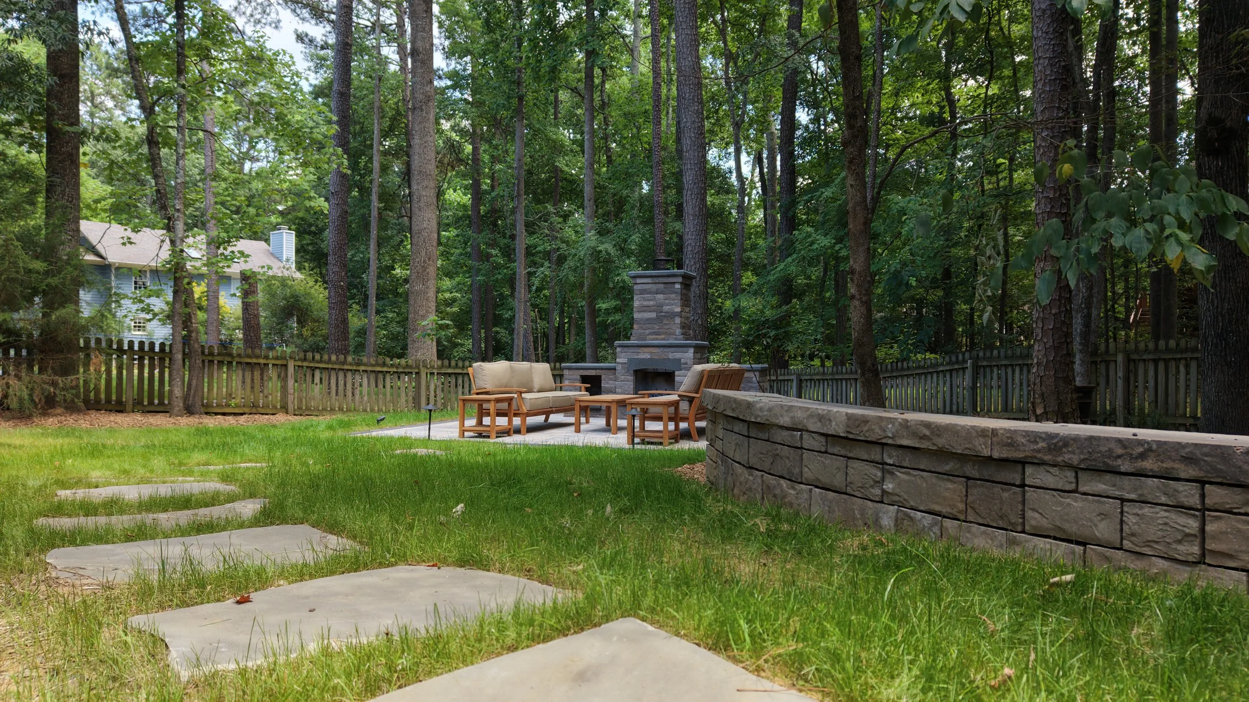 Outdoor living space including a fireplace, retaining wall, and stepping stones in Cary, NC