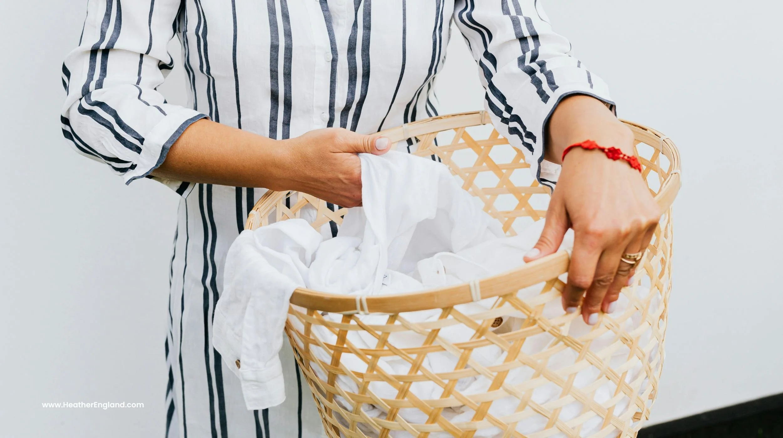 woman in white and grey striped dress holding laundry basket full of white clothes