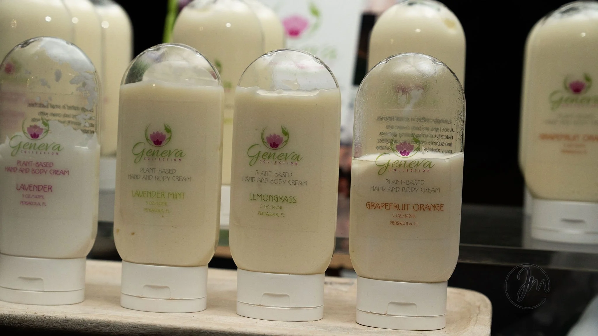 Bottles of plant-based hand and body cream with lavender, lavender mint, lemongrass, and grapefruit orange scents on display.