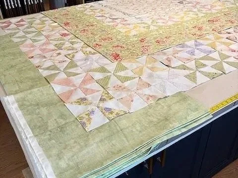 Pinwheels are all made and ready to sew together and attach to the original quilt.  Fabric possibilities for the new outer border are also being auditioned here.