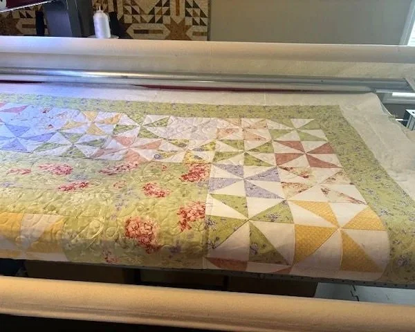 The enlarged quilt has been assembled and is now on the longarm to do the quilting process.  The only parts being quilted in this step are the areas that have been added.  All of the original quilting has been retained.