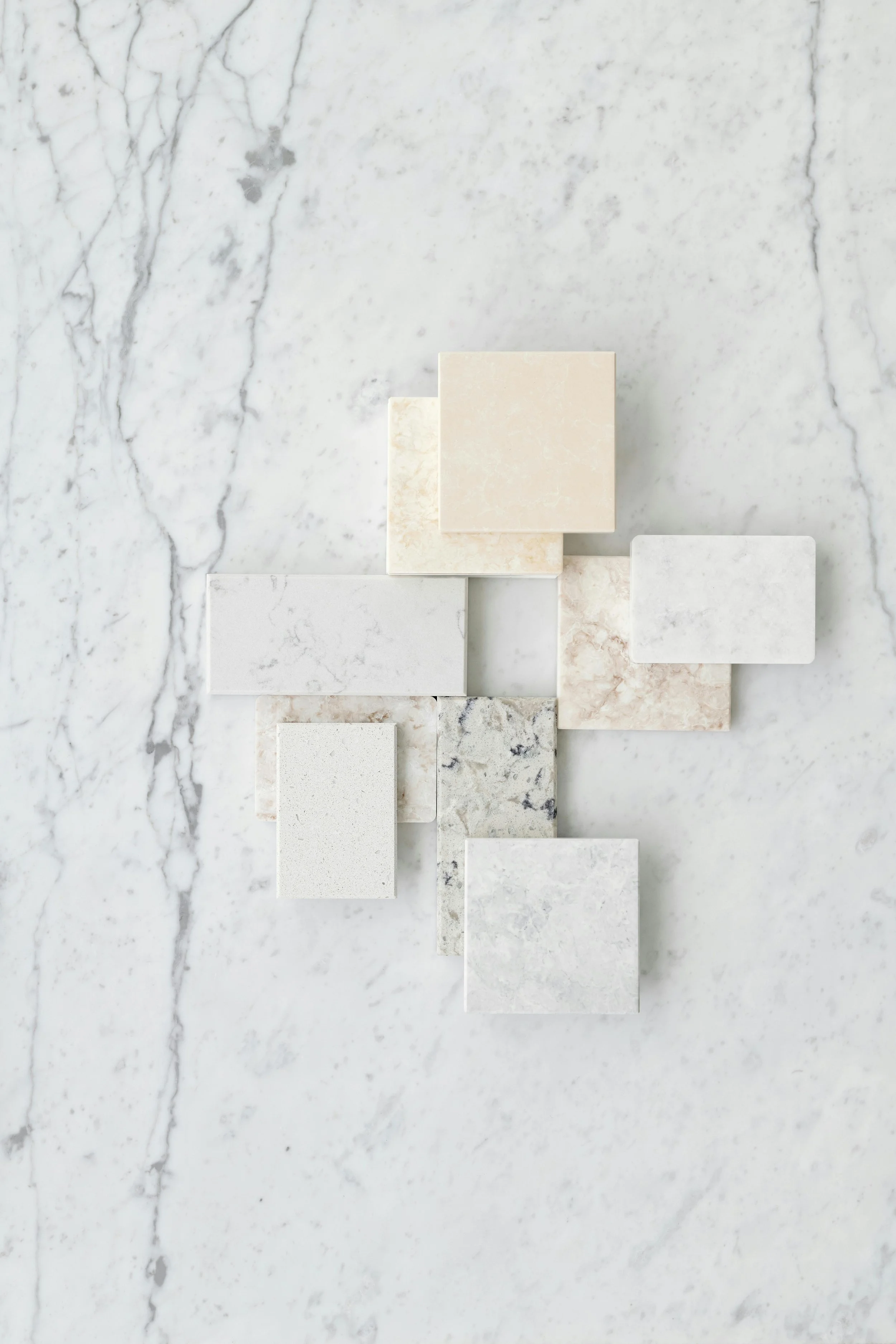 Various marble and stone tiles arranged on a white marble surface.