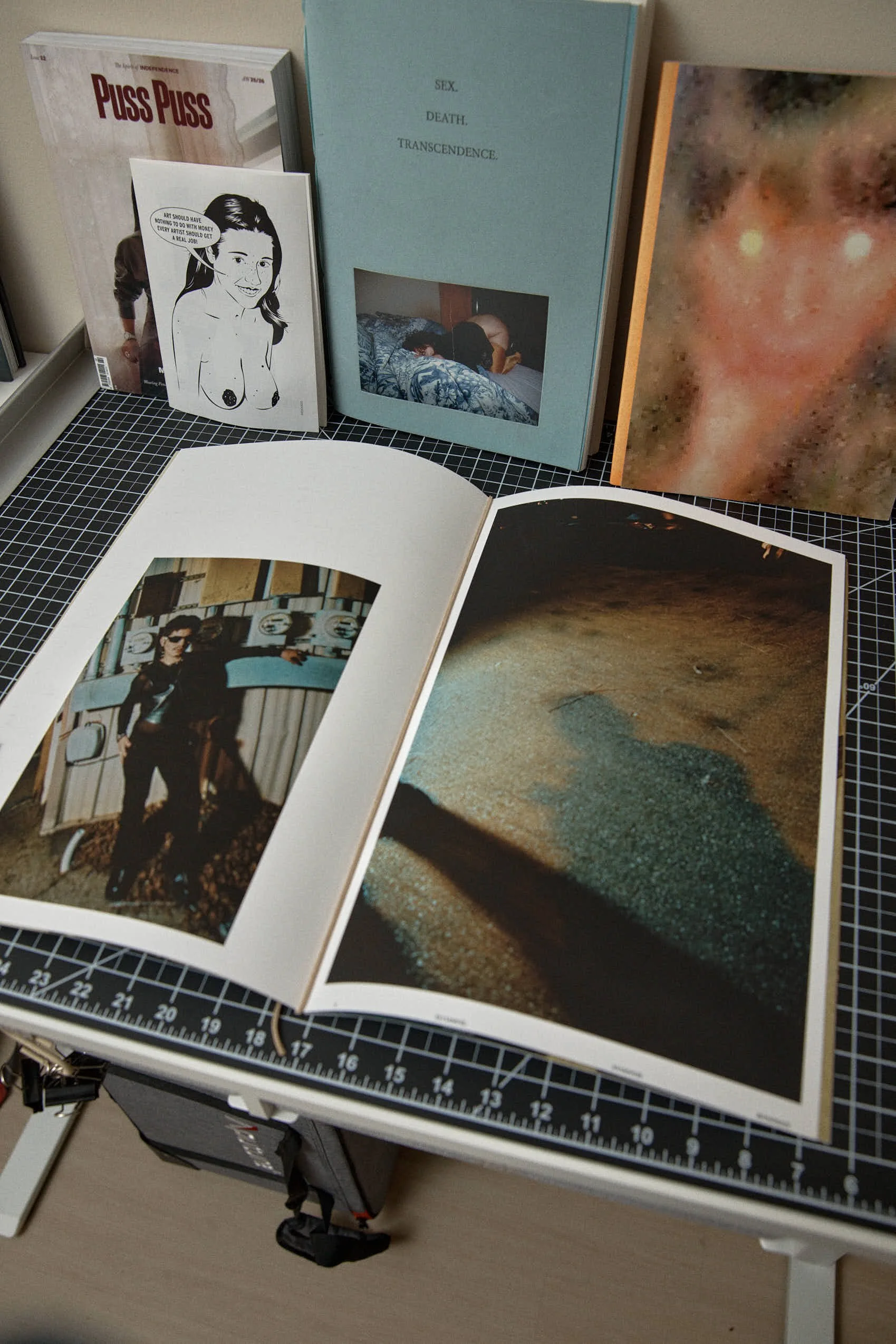 Collection of art and photography books displayed on a table, with some books opened to show photographs and illustrations.