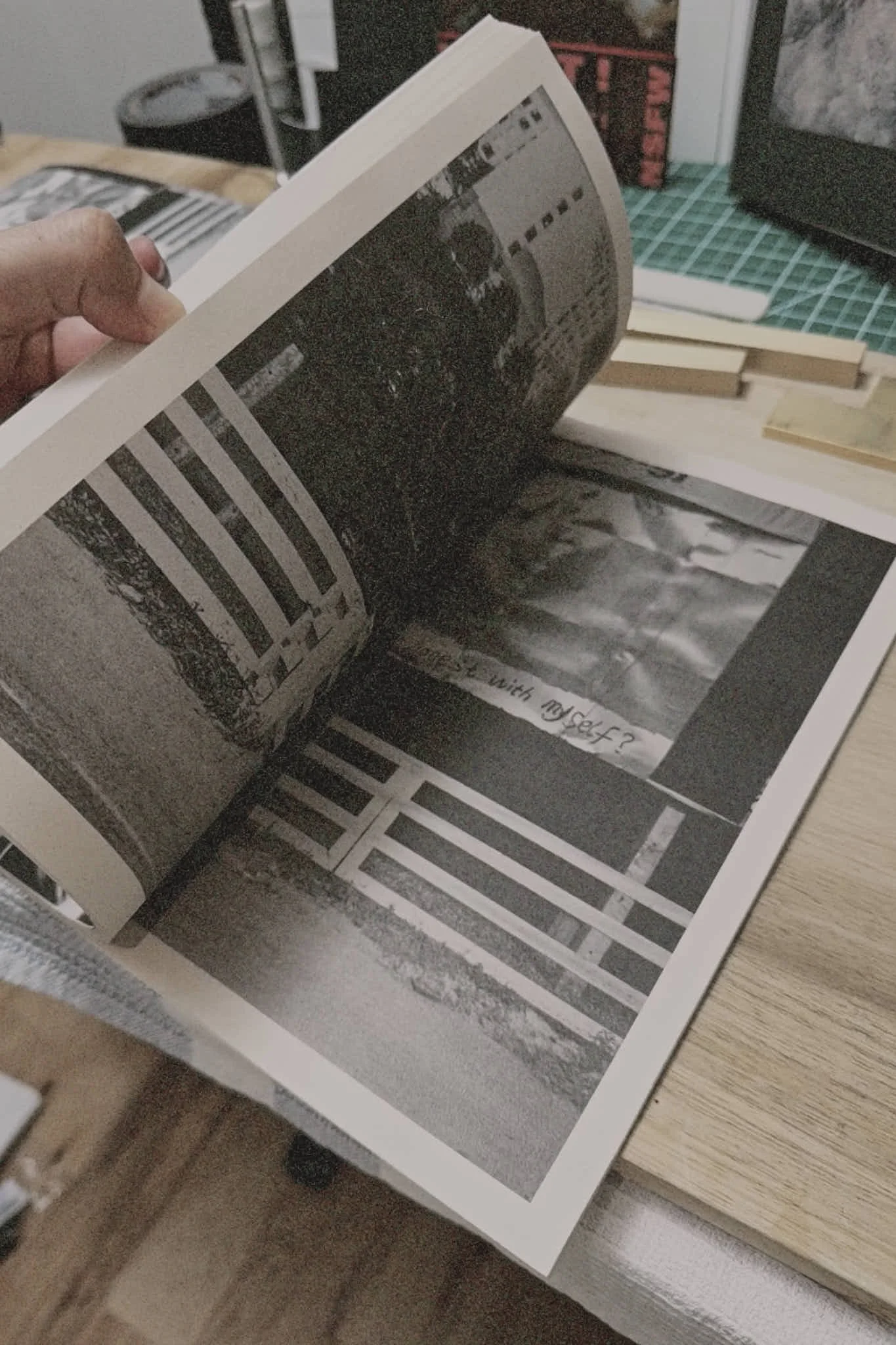 A person flipping through black-and-white photographs in a photo book on a desk.