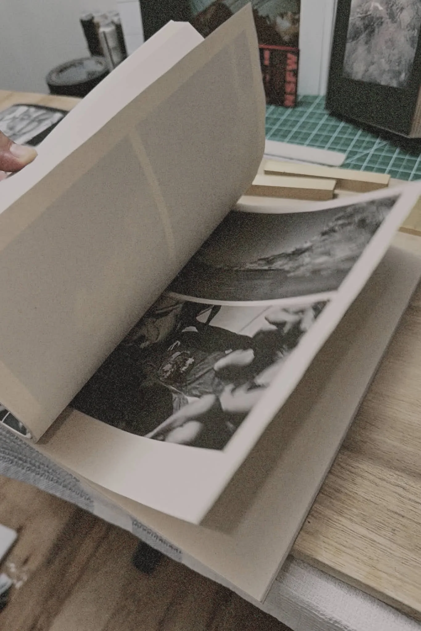 Open photo album with black and white photos on a wooden table.