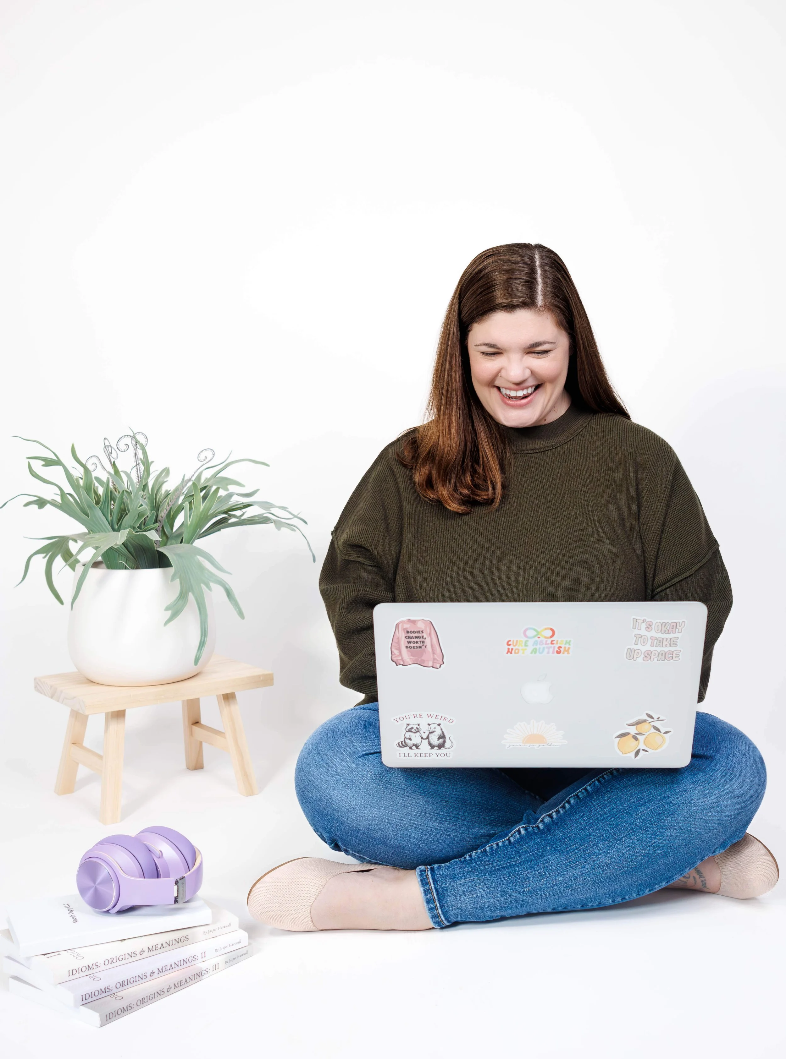 Sarah sitting on the floor, typing on her laptop with a smile.