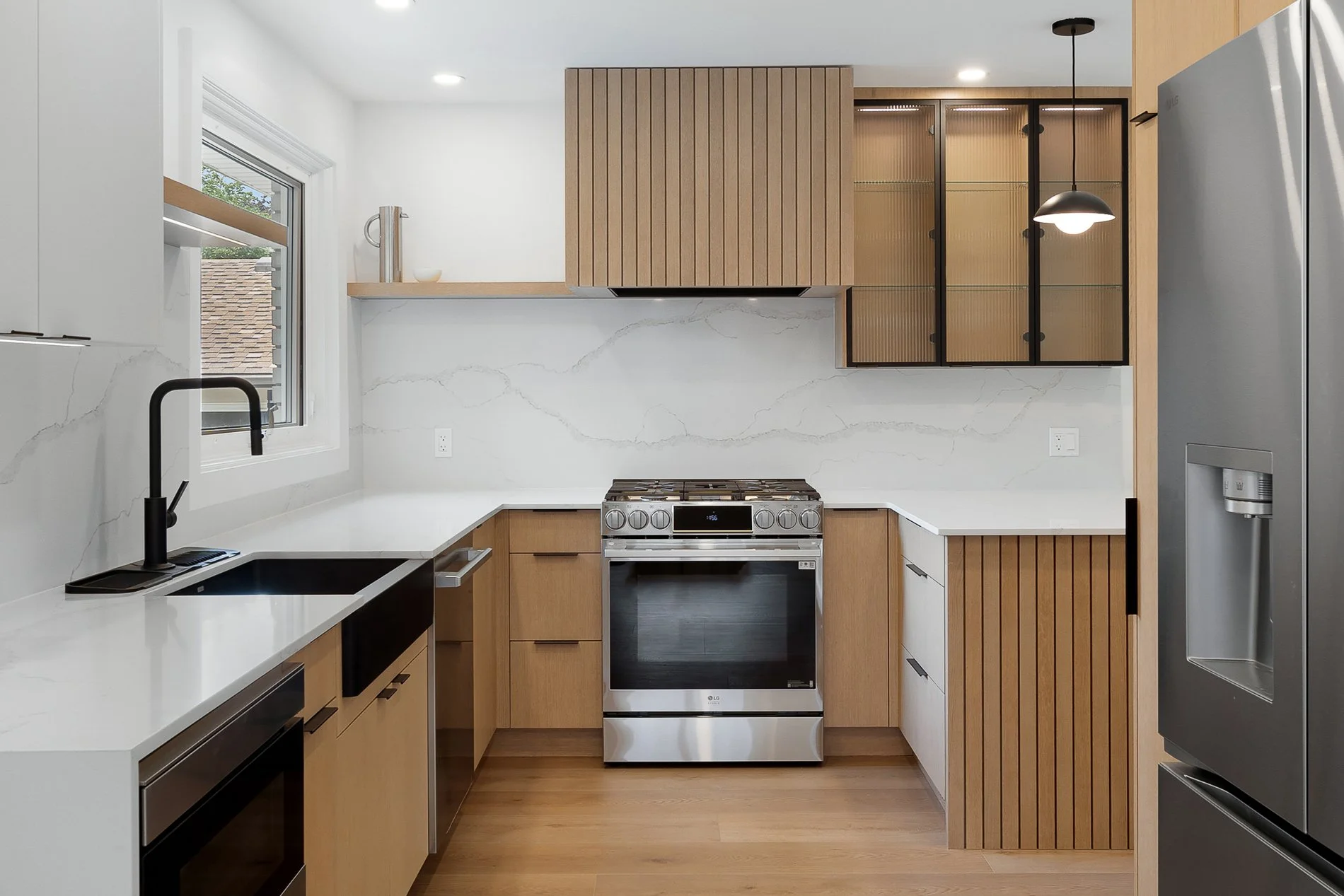 Modern kitchen with wooden cabinets, stainless steel appliances, black faucet, and marble countertops.