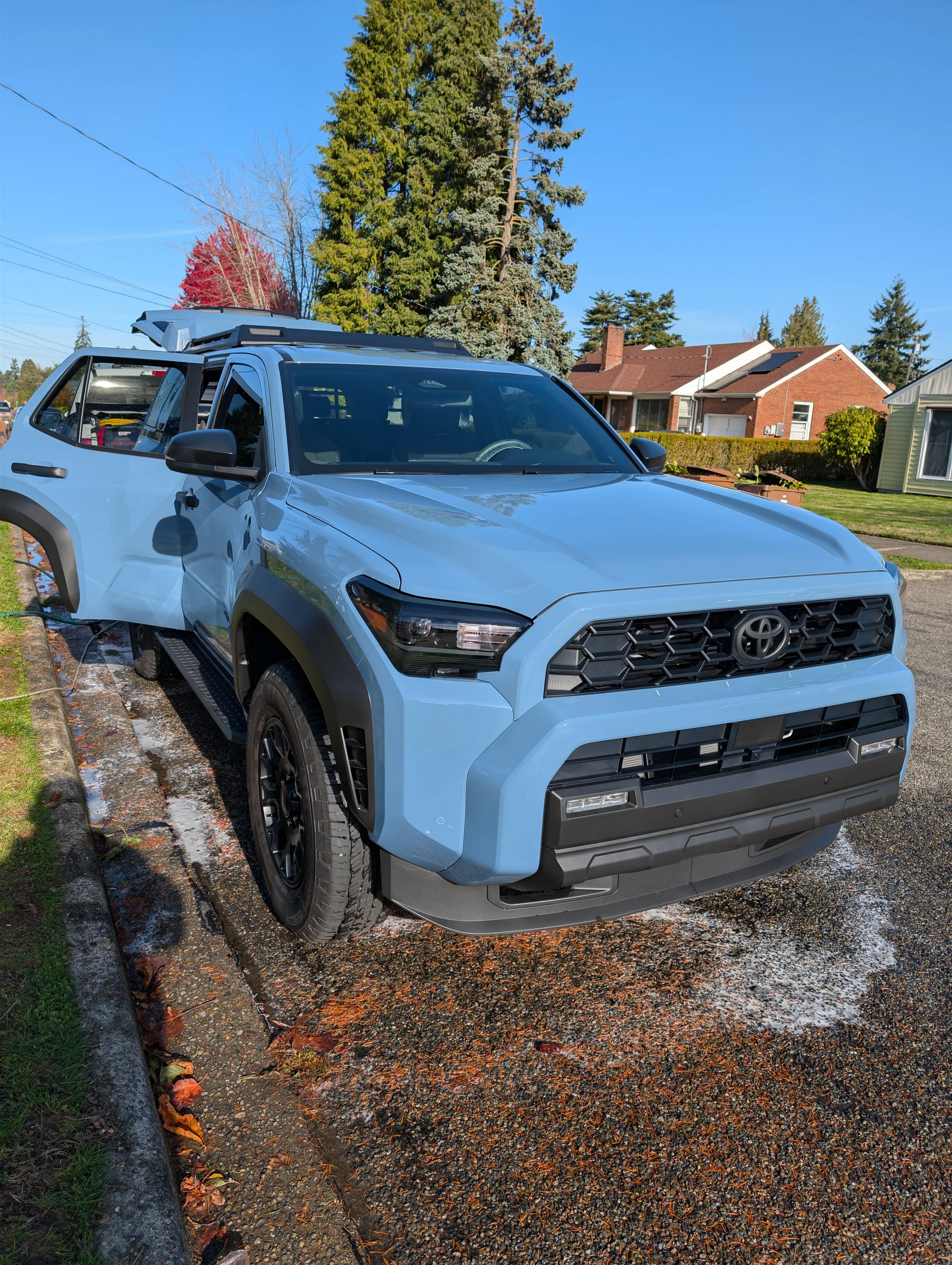 Blue SUV Toyota Rav4 parked on a driveway in front of a suburban house with trees and clear blue sky in the background. Mini Detail best bang for buck.
