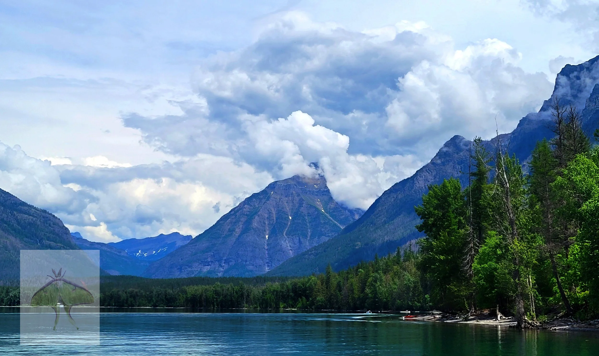 Lake McDonald (LE) - This tranquil deep jade colored lake is found in Glacier National Park.  In the far background canoes and kayaks are parked along the water's edge.  The huge cumulus clouds were the soft touch that added the perfect addition to t