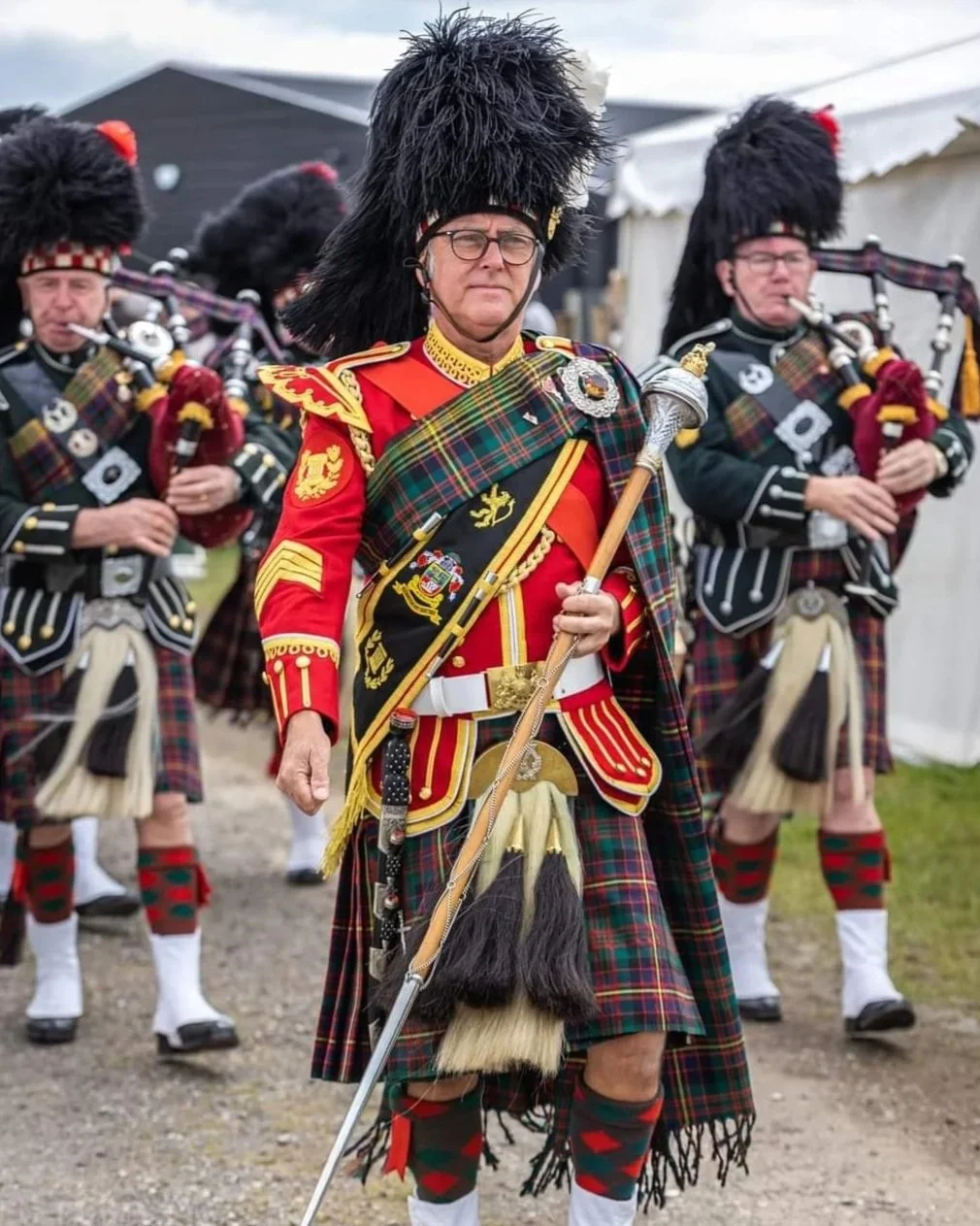 A group of men dressed in traditional Scottish military uniforms, including kilts, sporrans, and ostrich feather bonnets , participating in a parade or ceremony.
