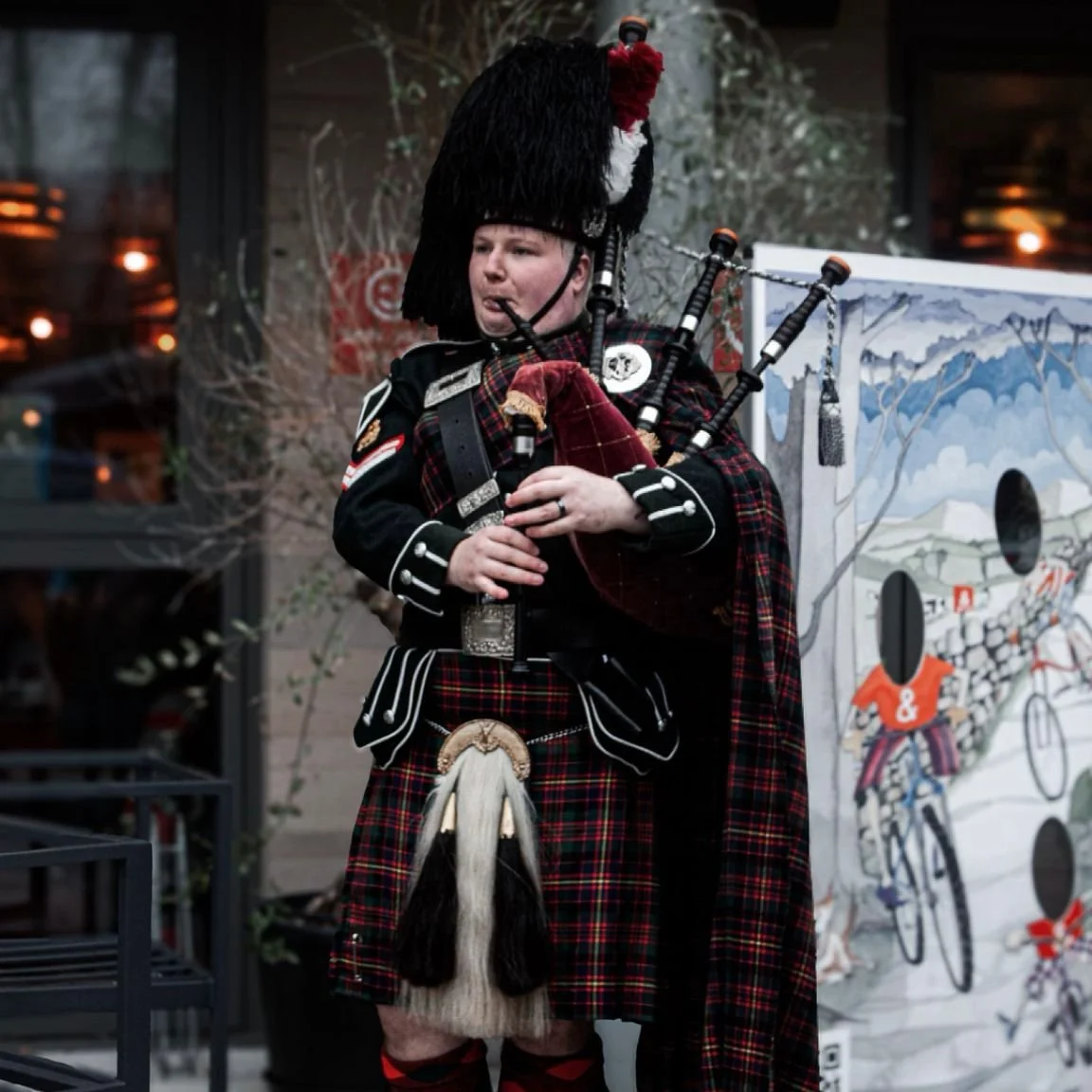 A person in traditional Scottish Highland dress playing bagpipes.