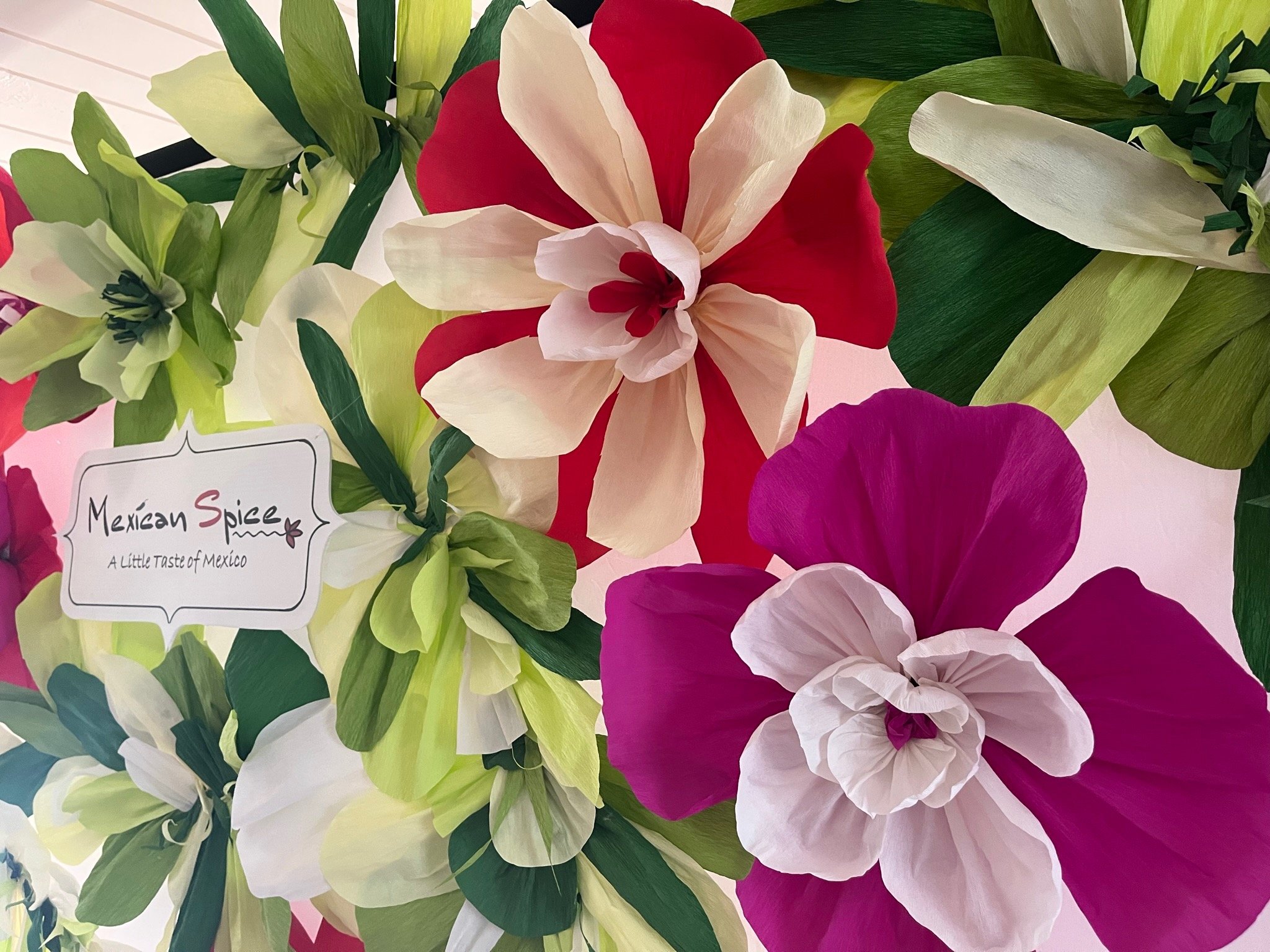 Colorful paper flowers with a sign reading "Mexican Spice: A Little Taste of Mexico."