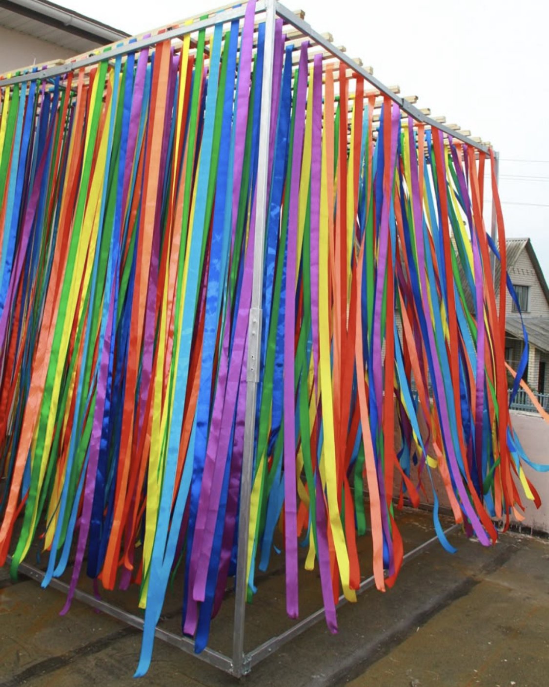 Colorful ribbons hanging from a metal frame forming a curtain-like structure.