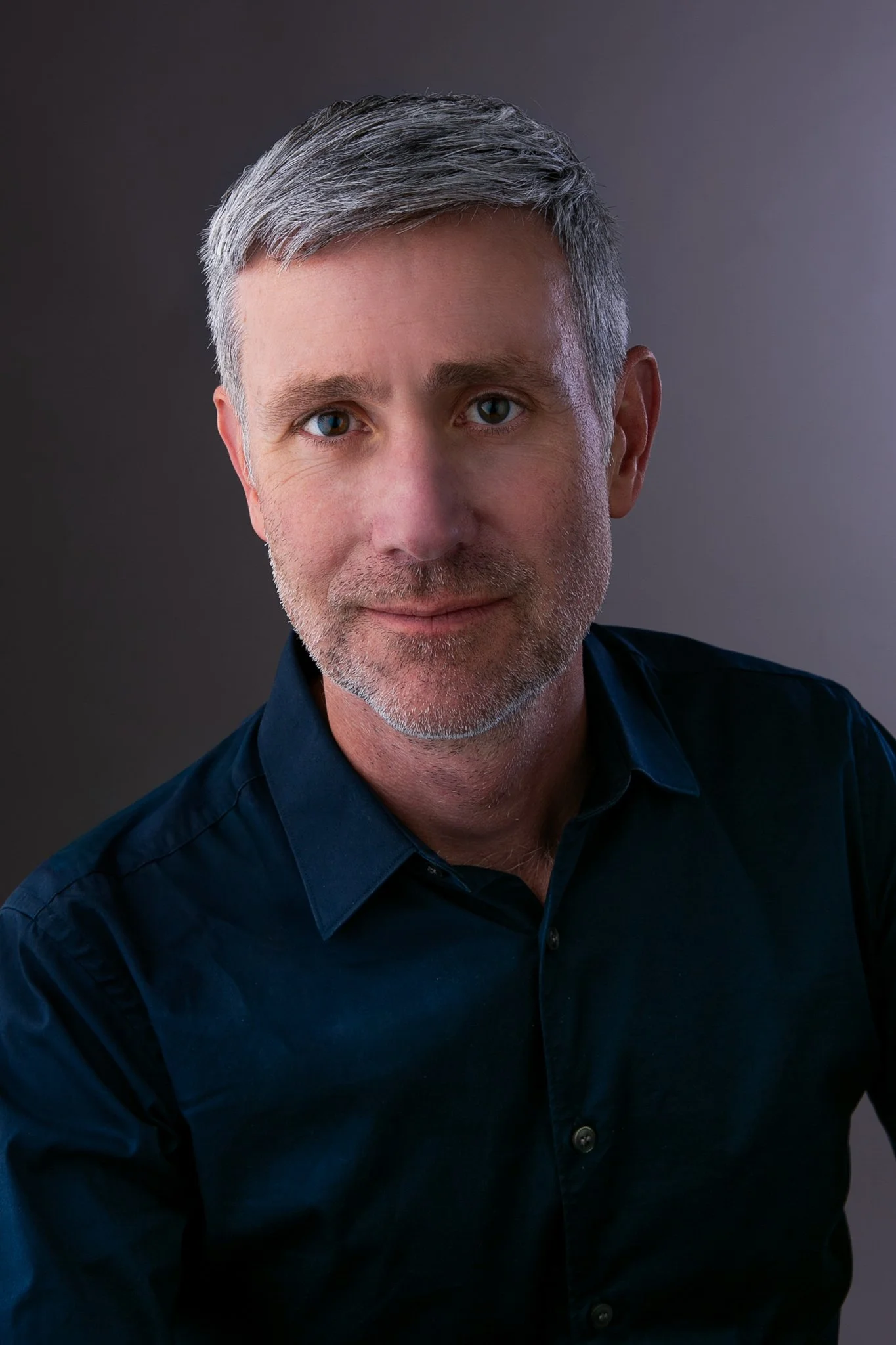 Black and white portrait of a man smiling, wearing a button-up shirt.
