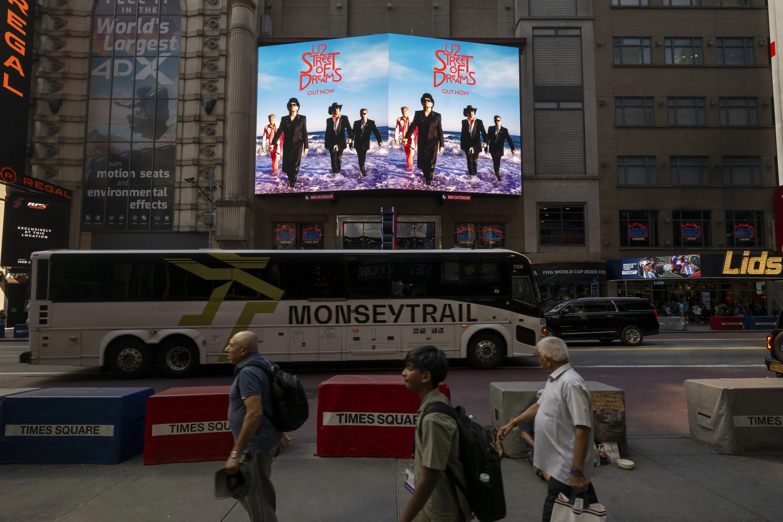 Large digital billboard displaying promotional art of The Rolling Stones walking on the beach with waves, for their album 'Street of Dreams,' with a blue sky background.