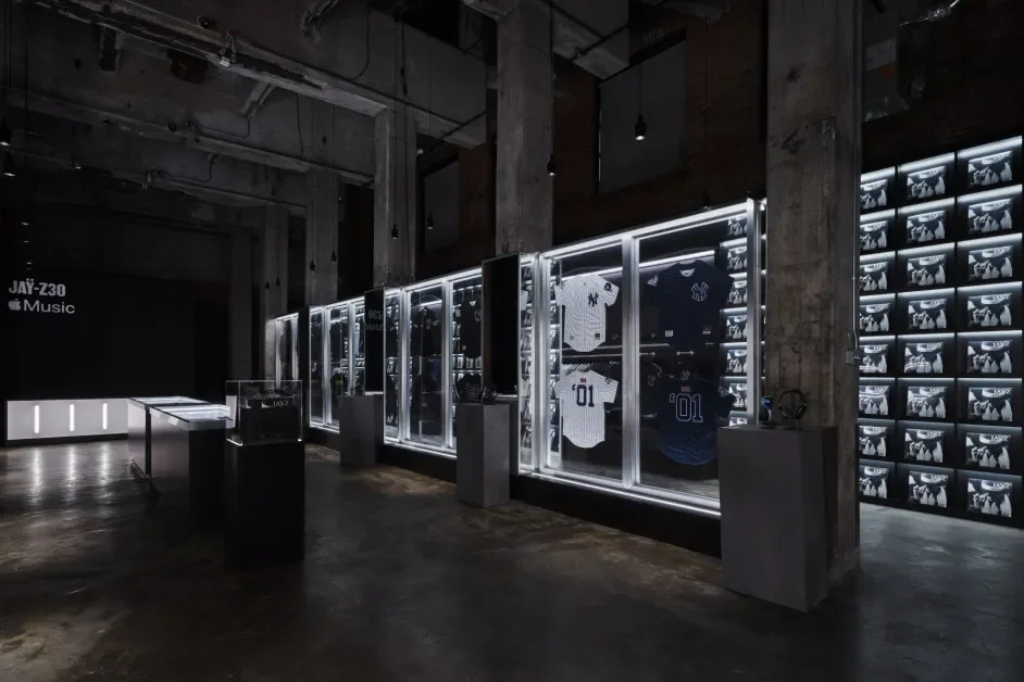 Display of sports jerseys and memorabilia in a dimly lit museum or exhibit space with concrete walls and floors.