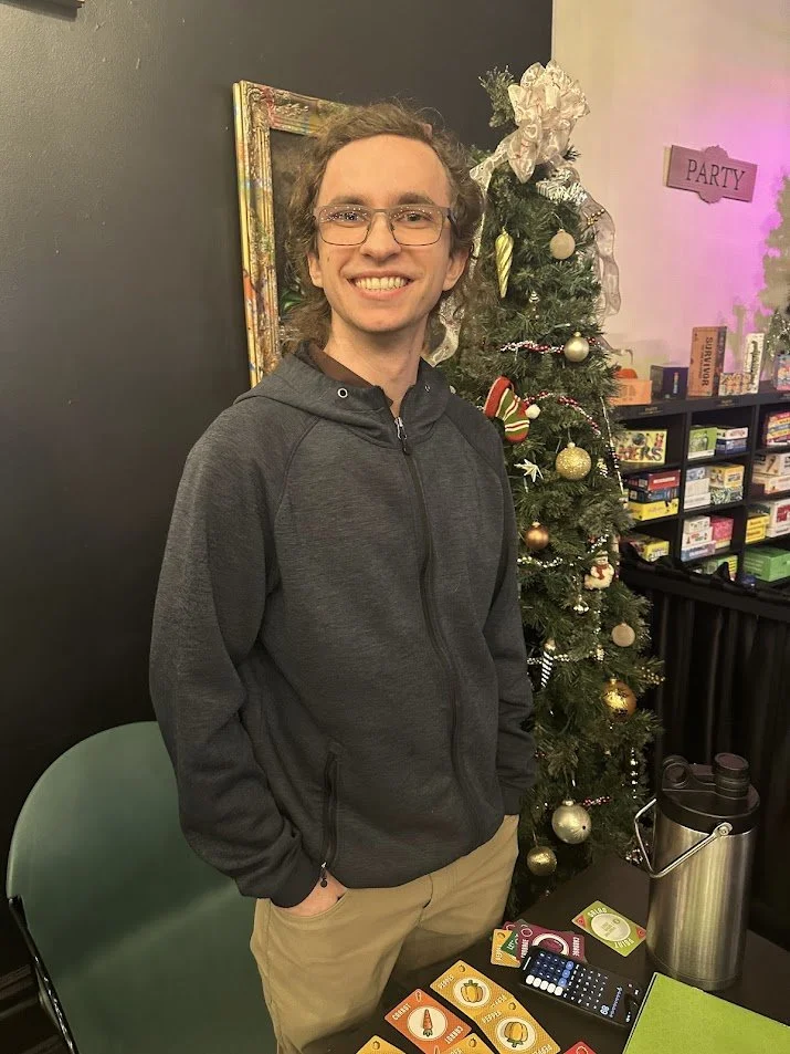 Gabe Luzynski in front of a Christmas tree at our Vegan Game Night and St. Louis Veganuary campaign meeting at Pieces Board Game Bar and Cafe in Soulard.jpg