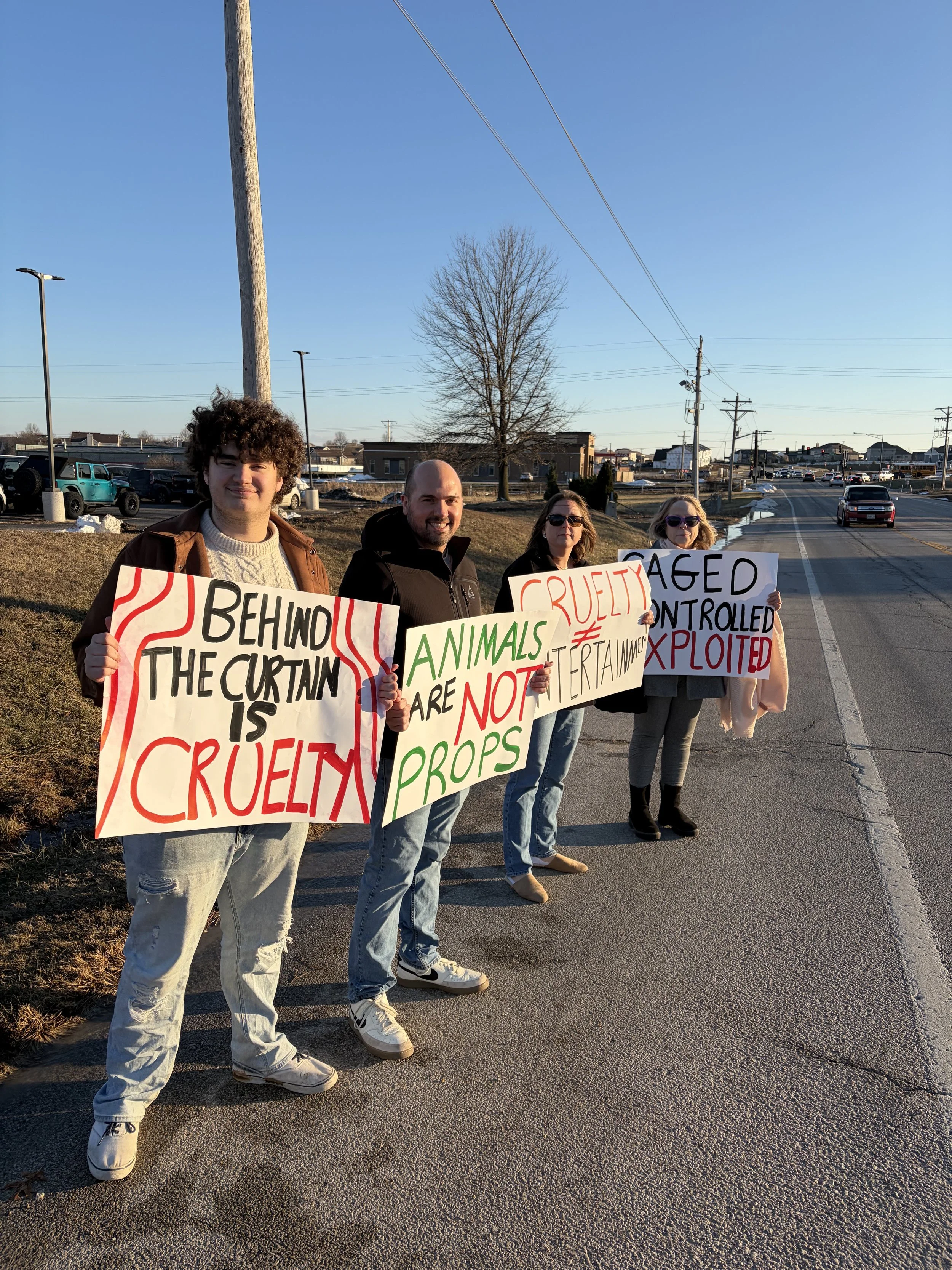 Andy holding a sign stating that animal cruelty is hidden behind the curtain.jpeg