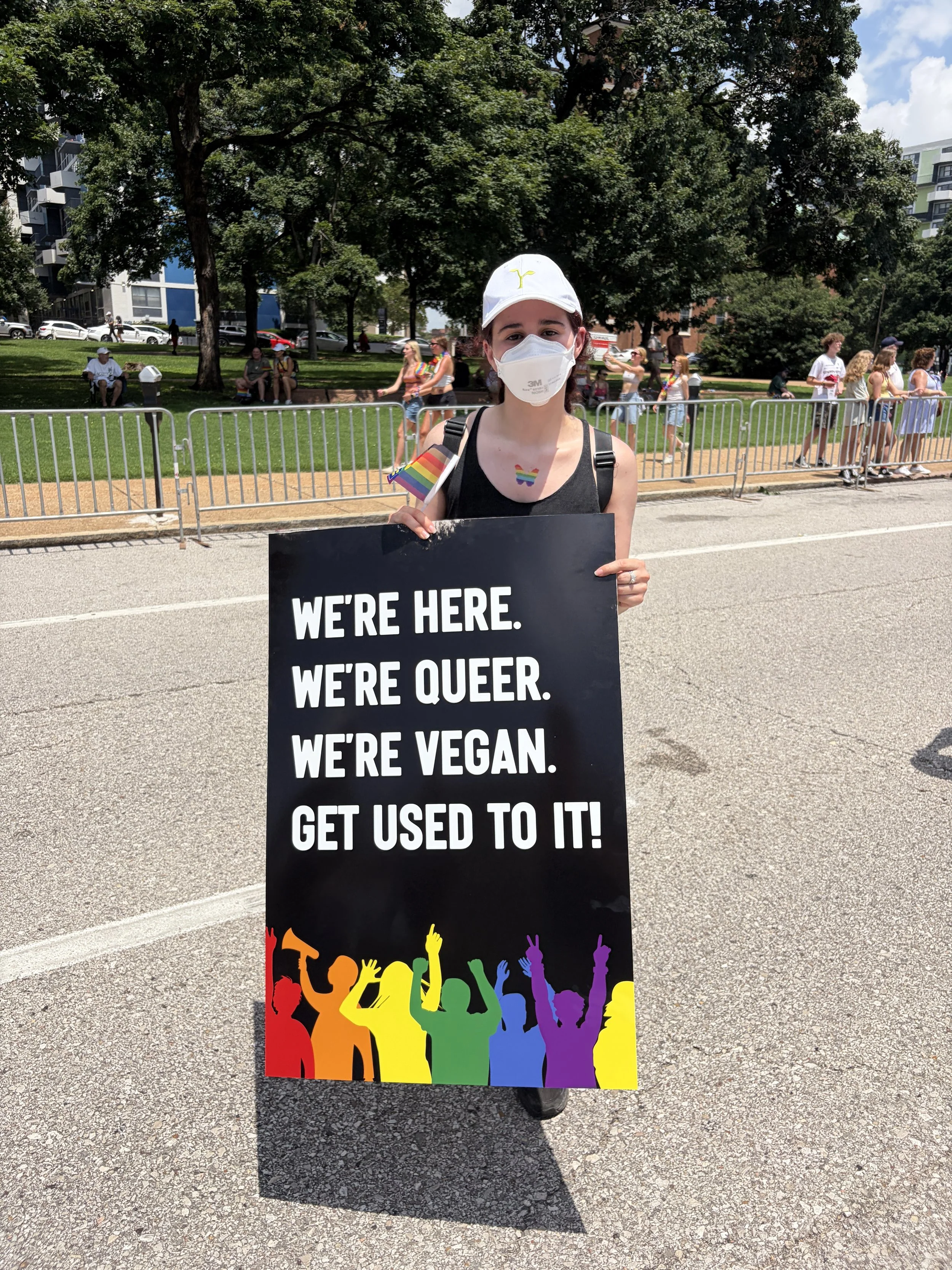 Emilee posing with her sign that states we_re here, queer, and vegan at the end of our Vegan Pride Parade.jpg