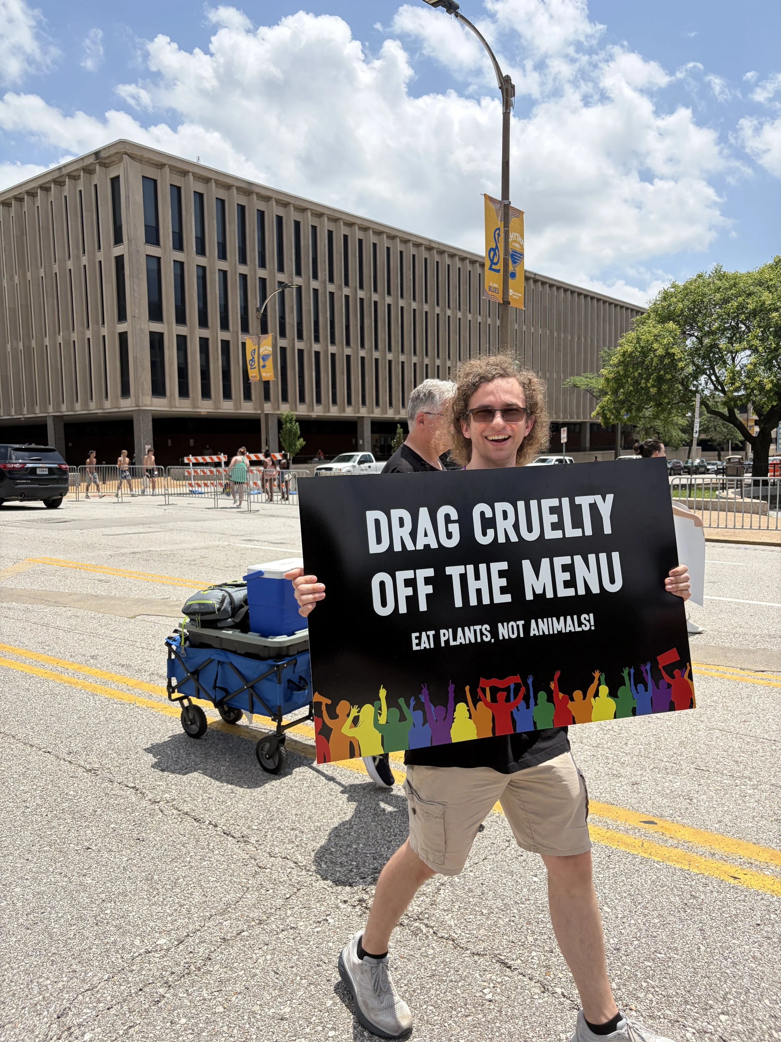 Gabe Luzynski carrying a sign that urges people to drag cruelty off the menu and eat plants instead of animals.jpg