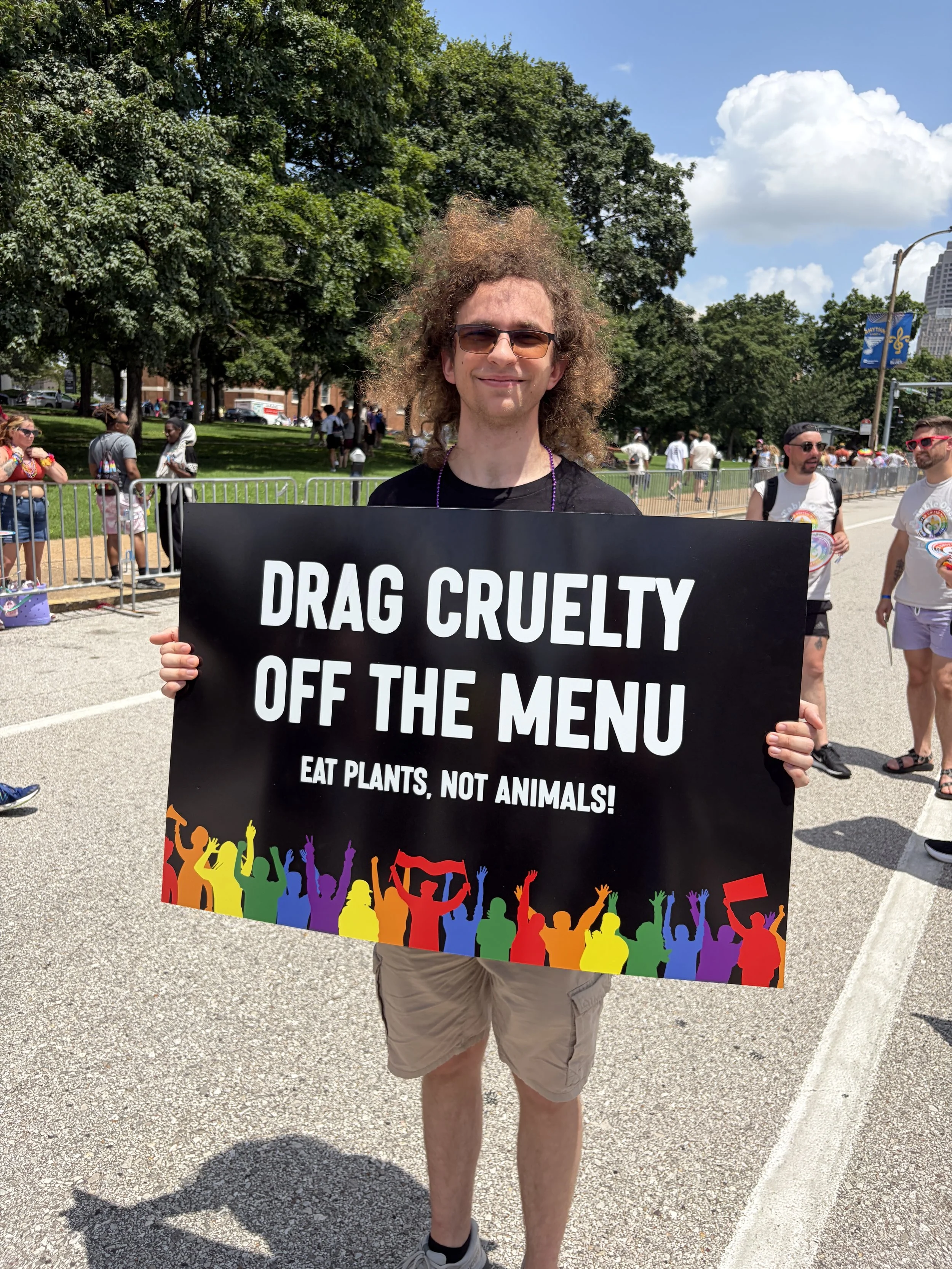 Gabe Luzynski smiling while holding his sign demanding we drag cruelty off the menu.jpg
