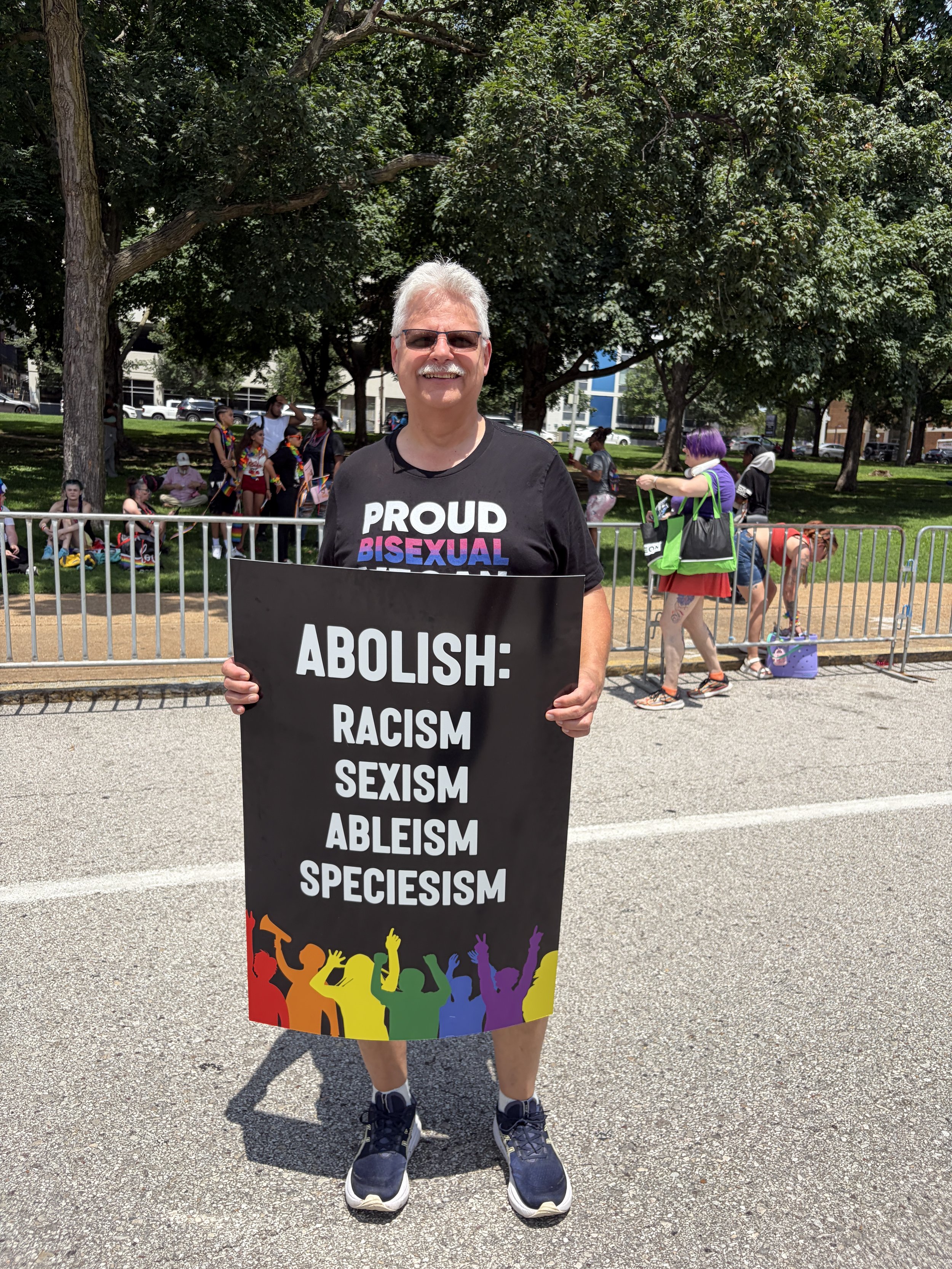 John Luzynski holding a sign that demands we abolish racism, sexism, ableism, and speciesism.jpg