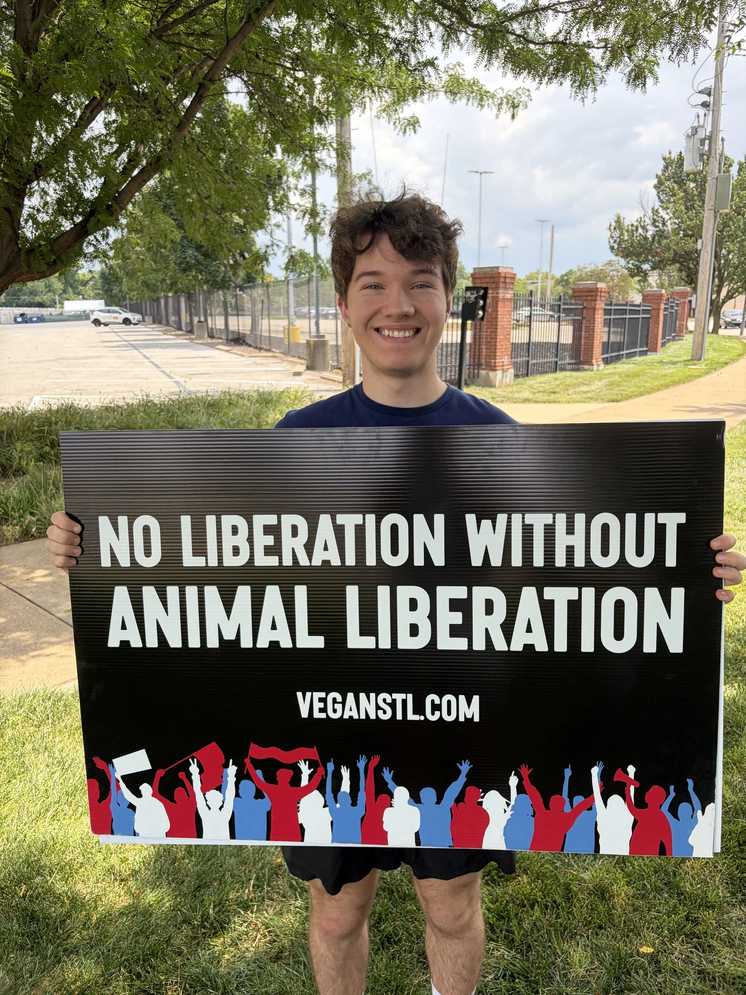 Augustus holding a sign that declares no liberation without animal liberation after our Animal Freedom March