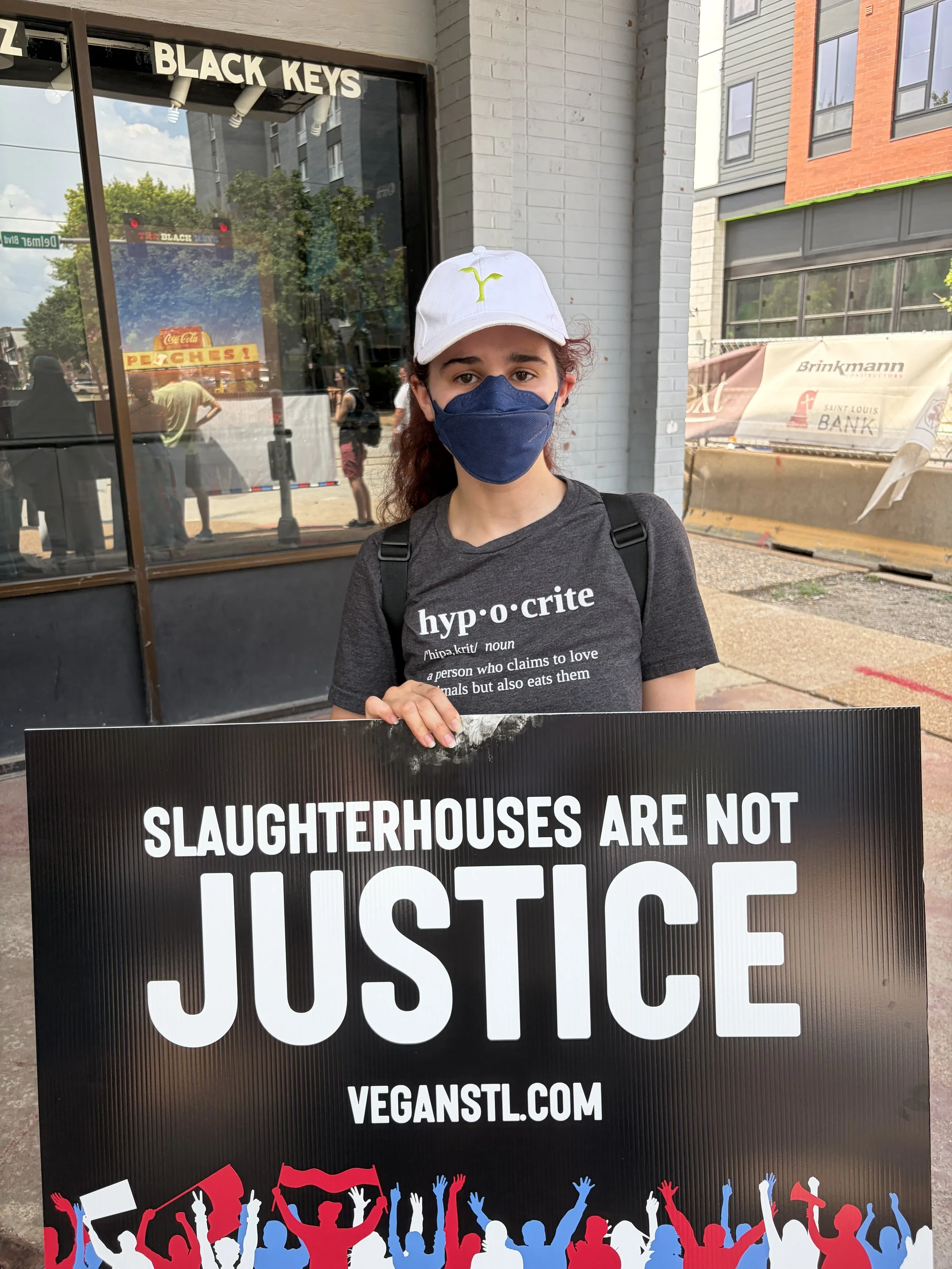 Emilee holding a sign that reads slaughterhouses are not justice while wearing a pro-vegan t-shirt at our Animal Freedom March