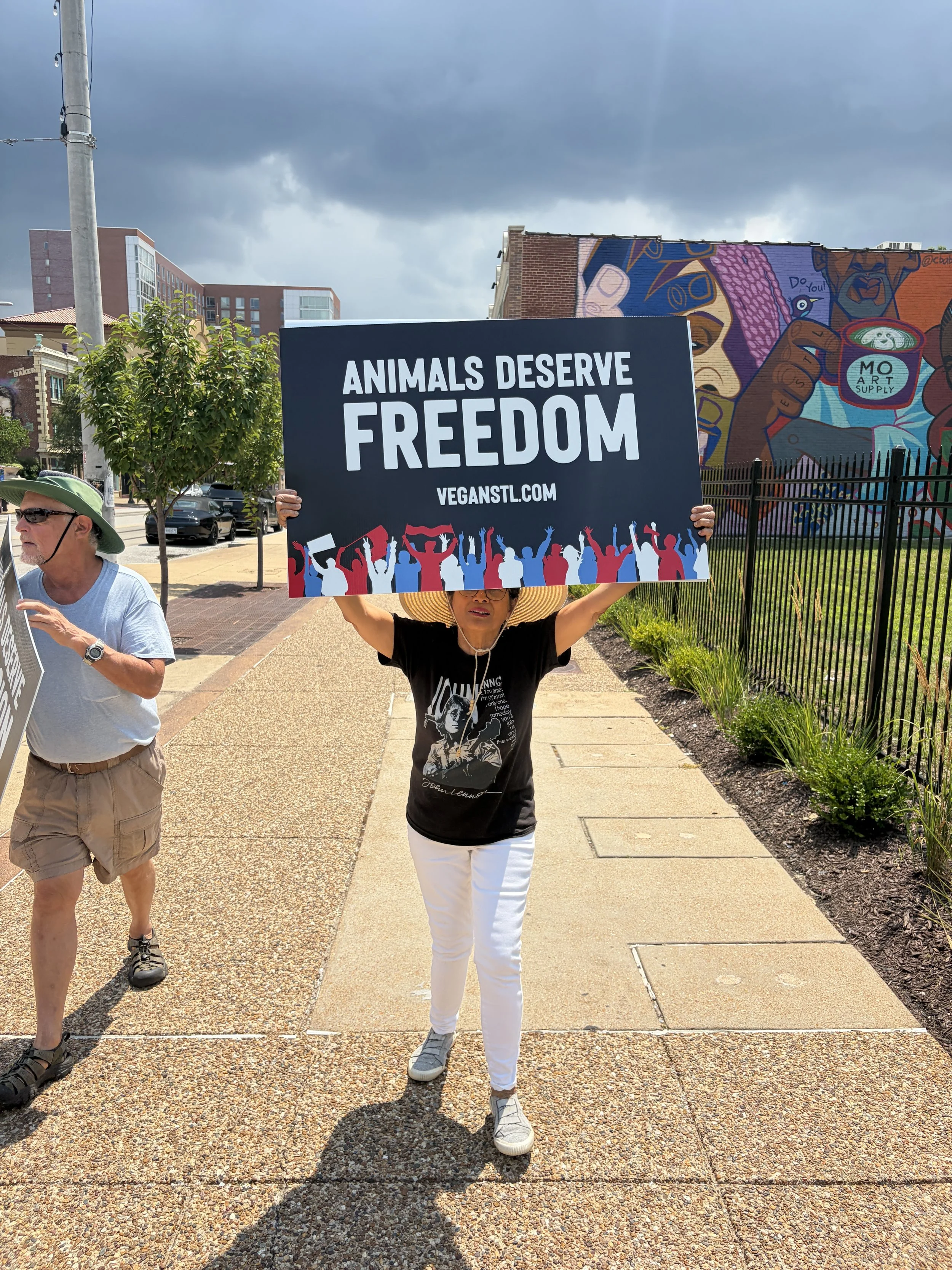 Hera Gerber carrying a sign that states animals deserve freedom at our Animal Freedom March with the sun peaking out