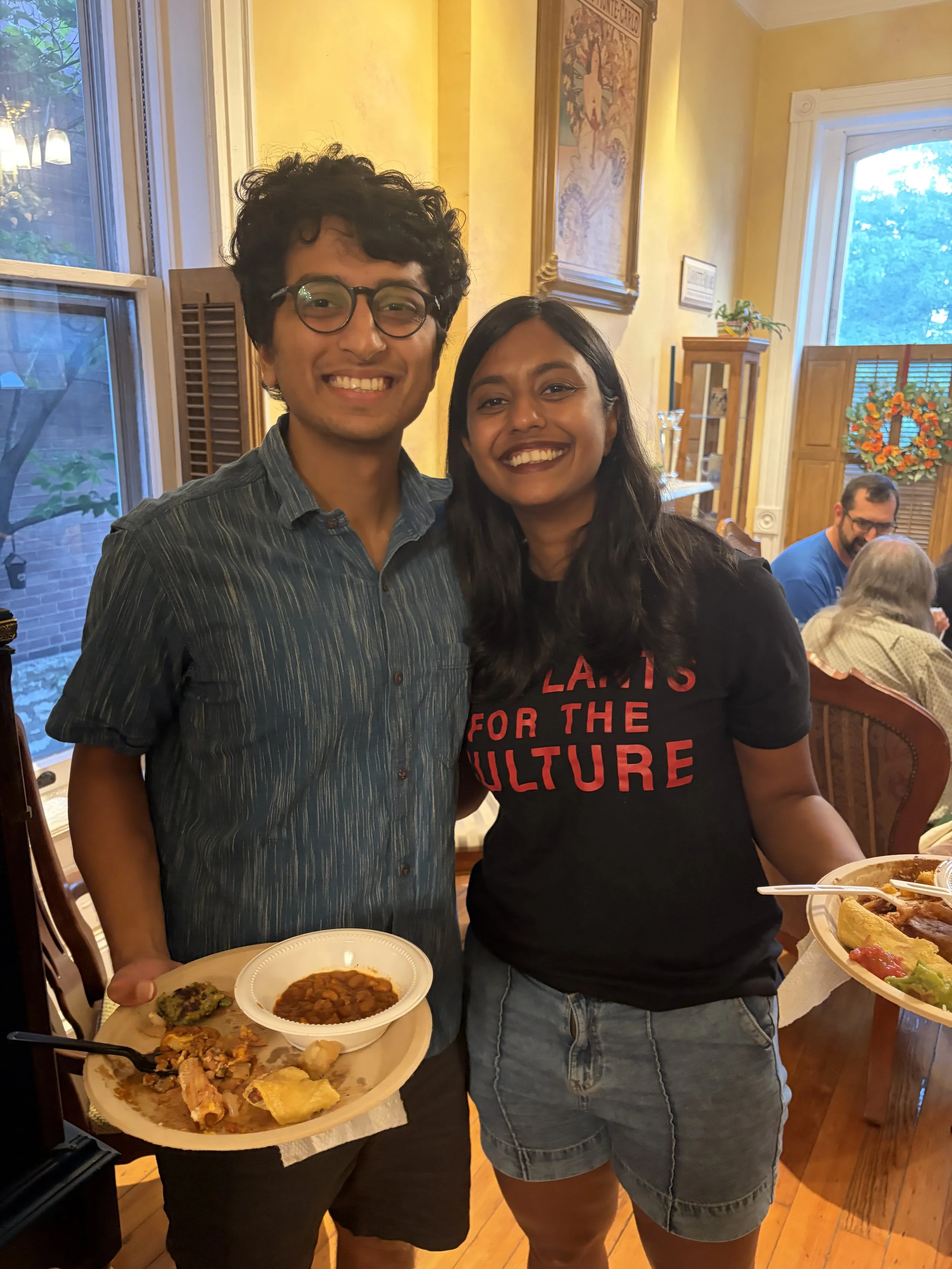 Attendees of Plant Lovers Potluck pose for a photo, with plates full of vegan dishes in St. Louis, Missouri.png